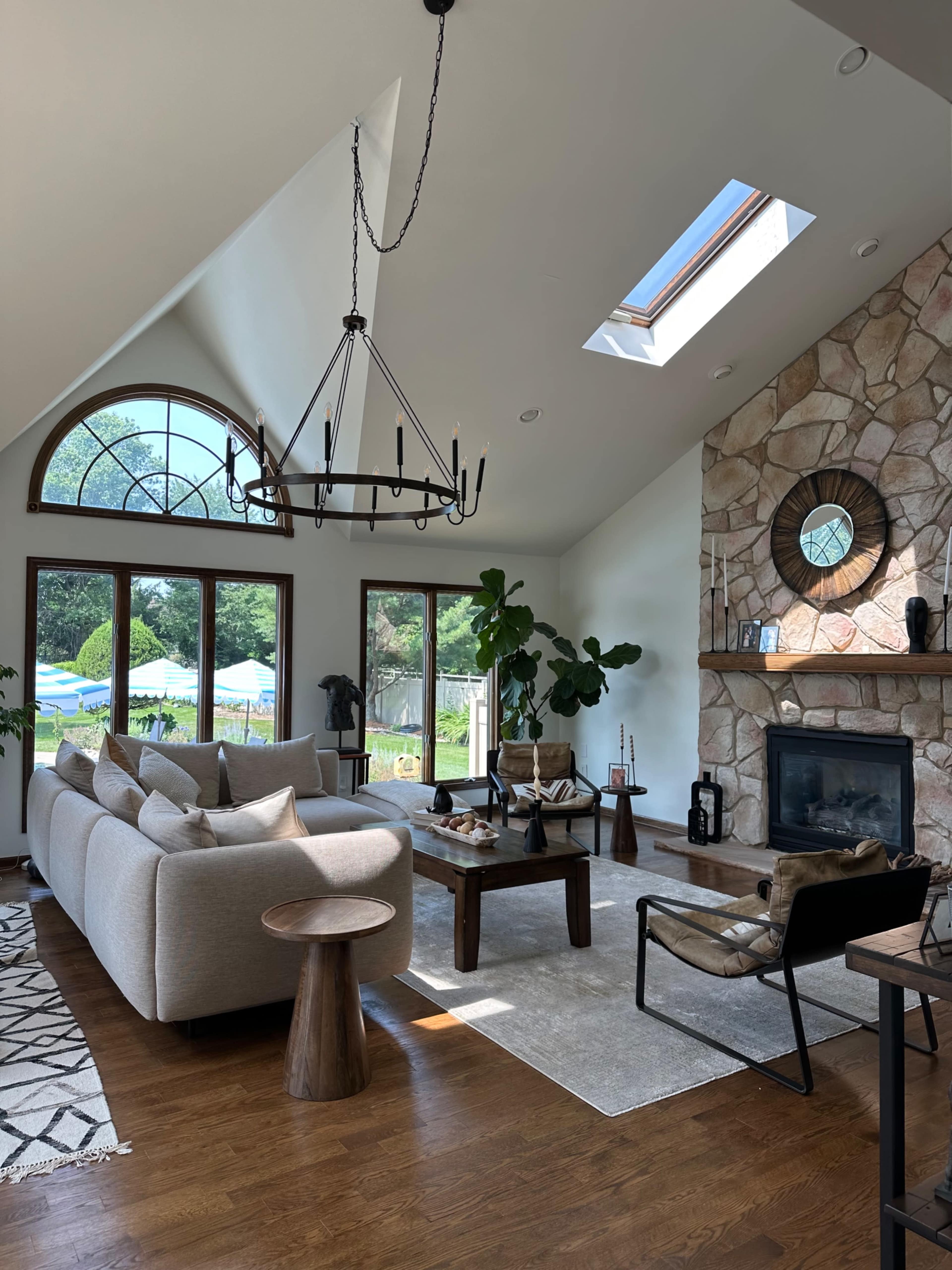 The living room features a cozy arrangement with a large sectional sofa, a stone fireplace, and multiple window views providing natural light.