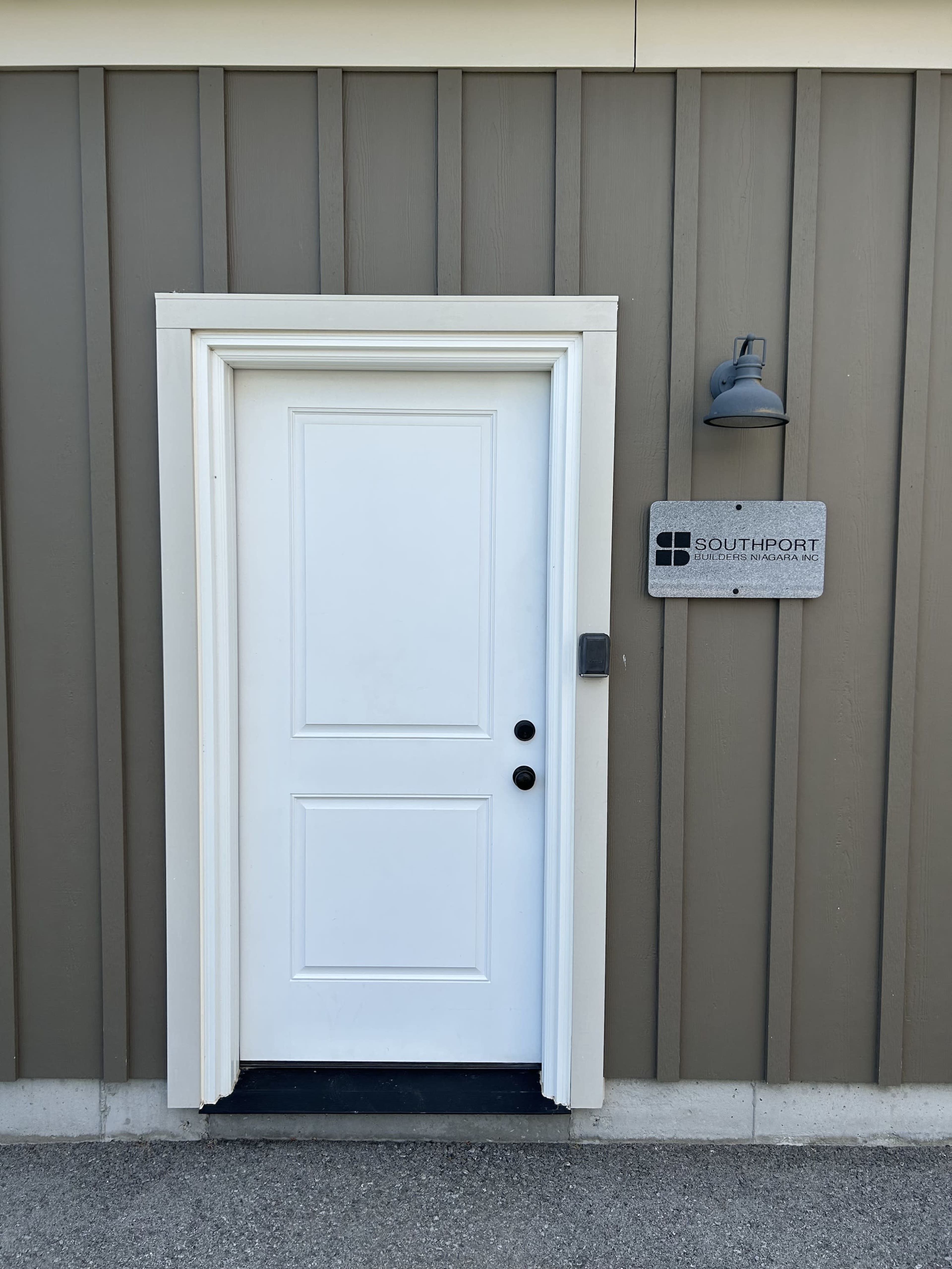 A white door with a black handle on a wall with brown paneling, accompanied by a sign that reads "SOUTHPORT."