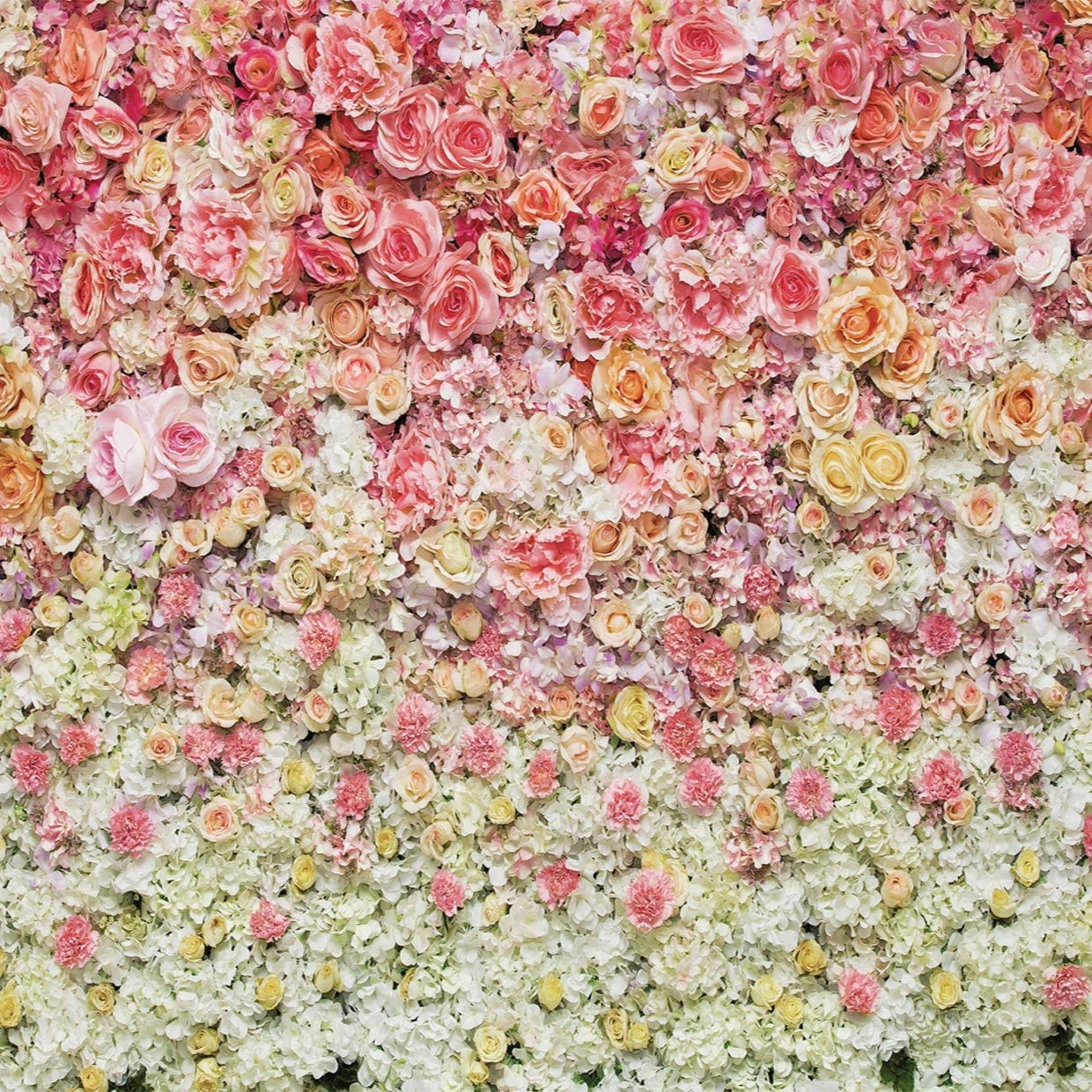 A wall covered with a dense arrangement of various pink, white, and cream flowers.