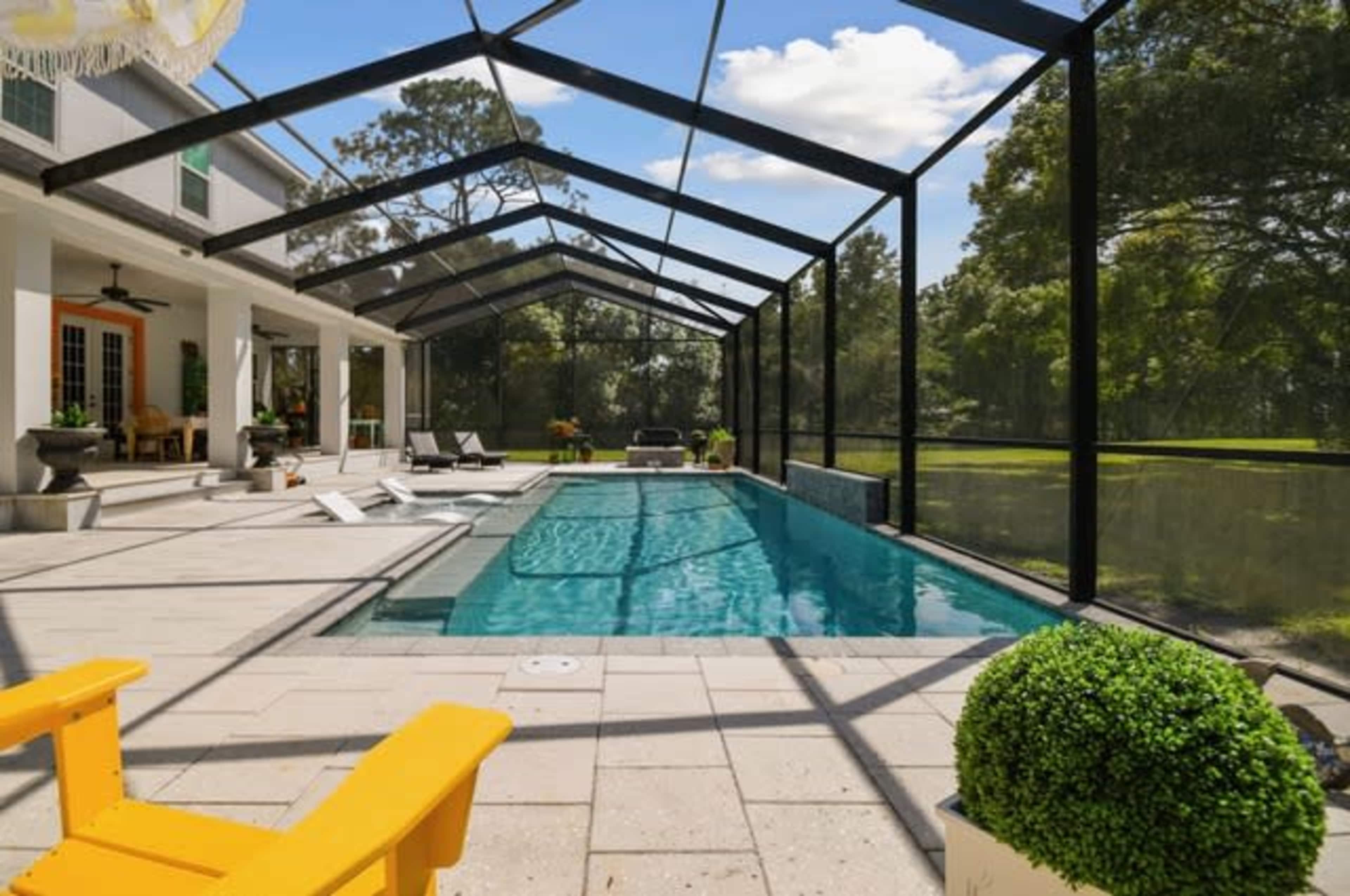 The image shows a screened-in pool area with a clean swimming pool, lounging chairs, and a landscaped backyard.