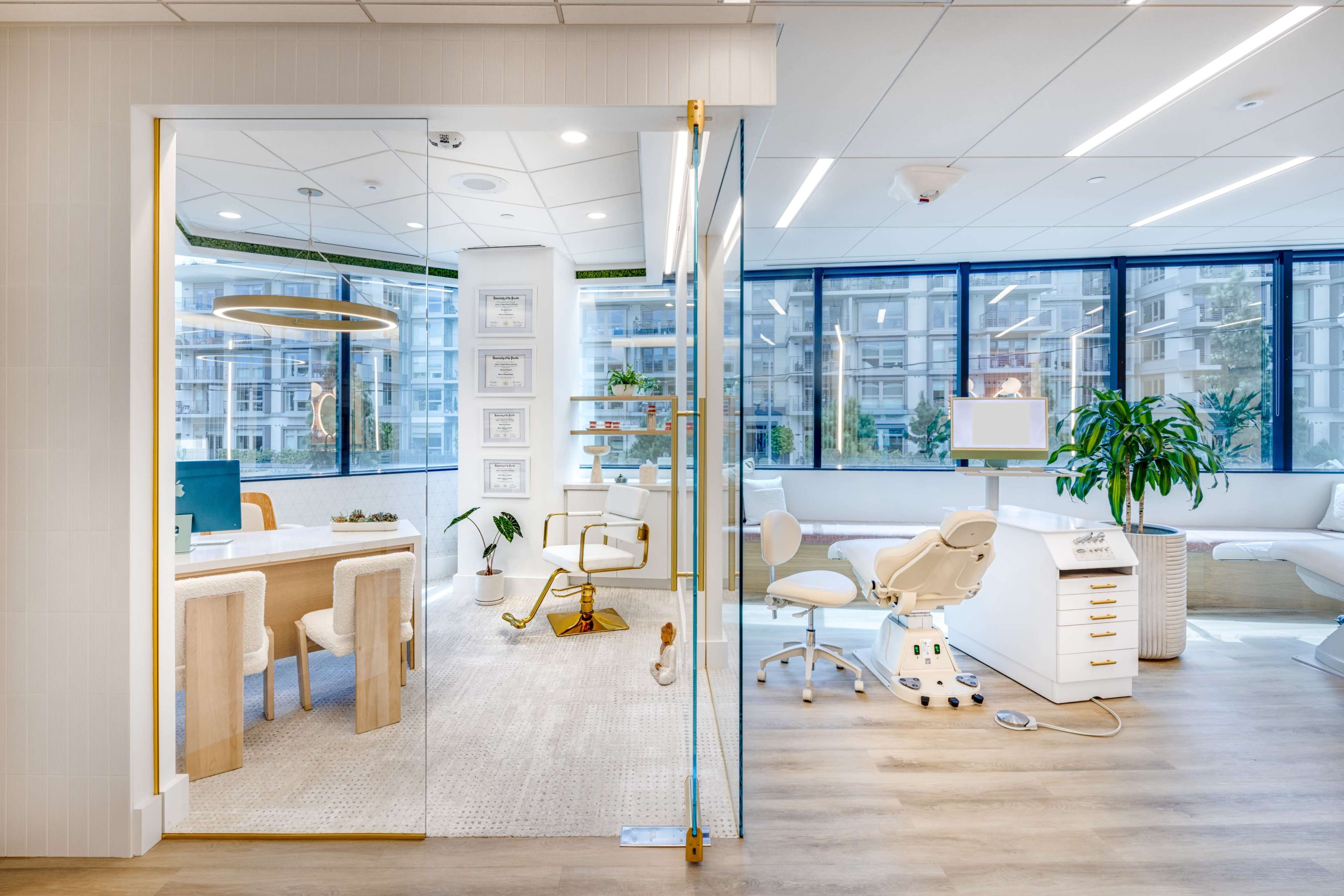 The image shows a modern dental office featuring a reception area with a large window and a treatment area equipped with dental chairs and equipment.