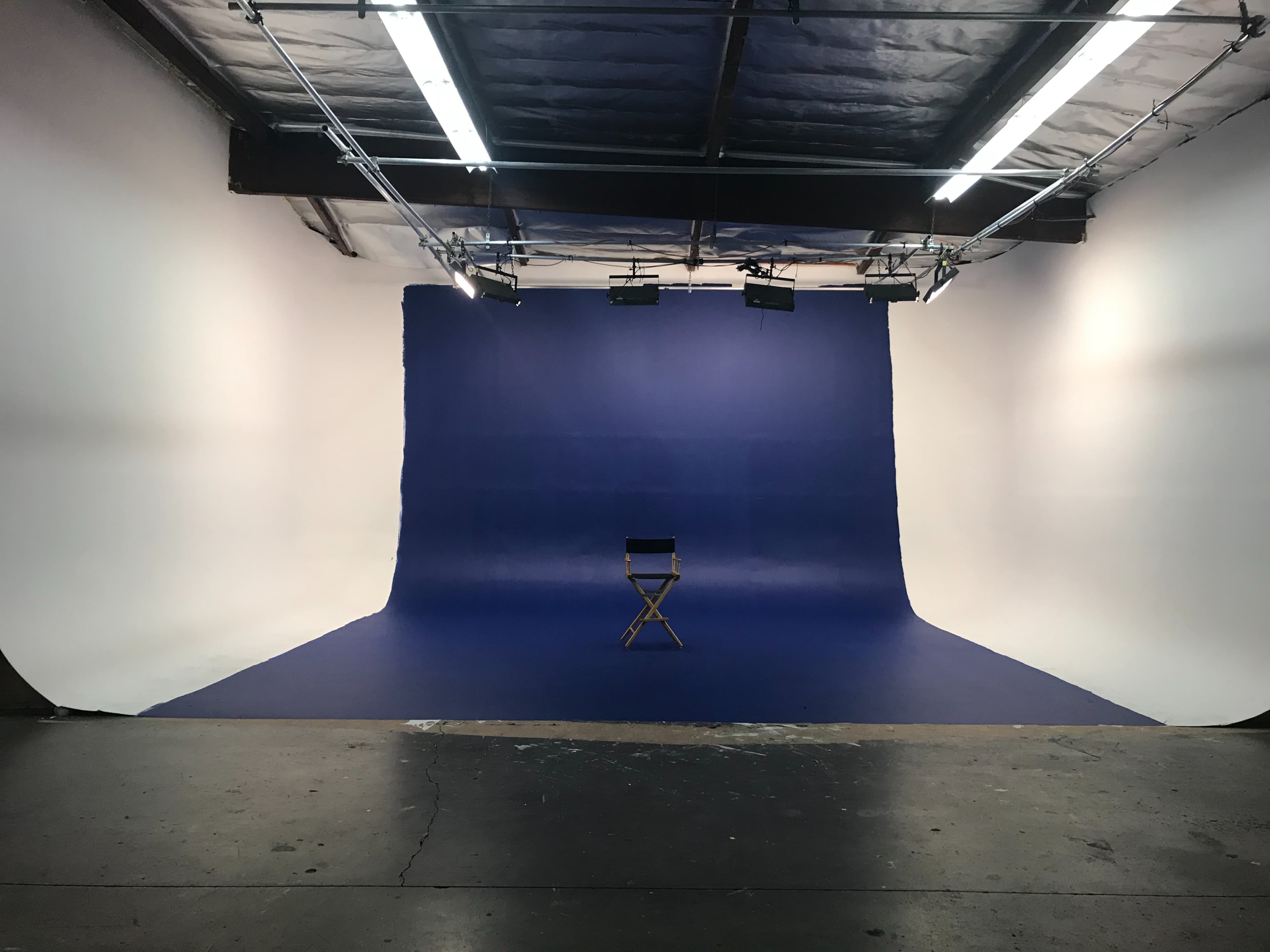 A studio space with a blue backdrop and a single director's chair in the center.