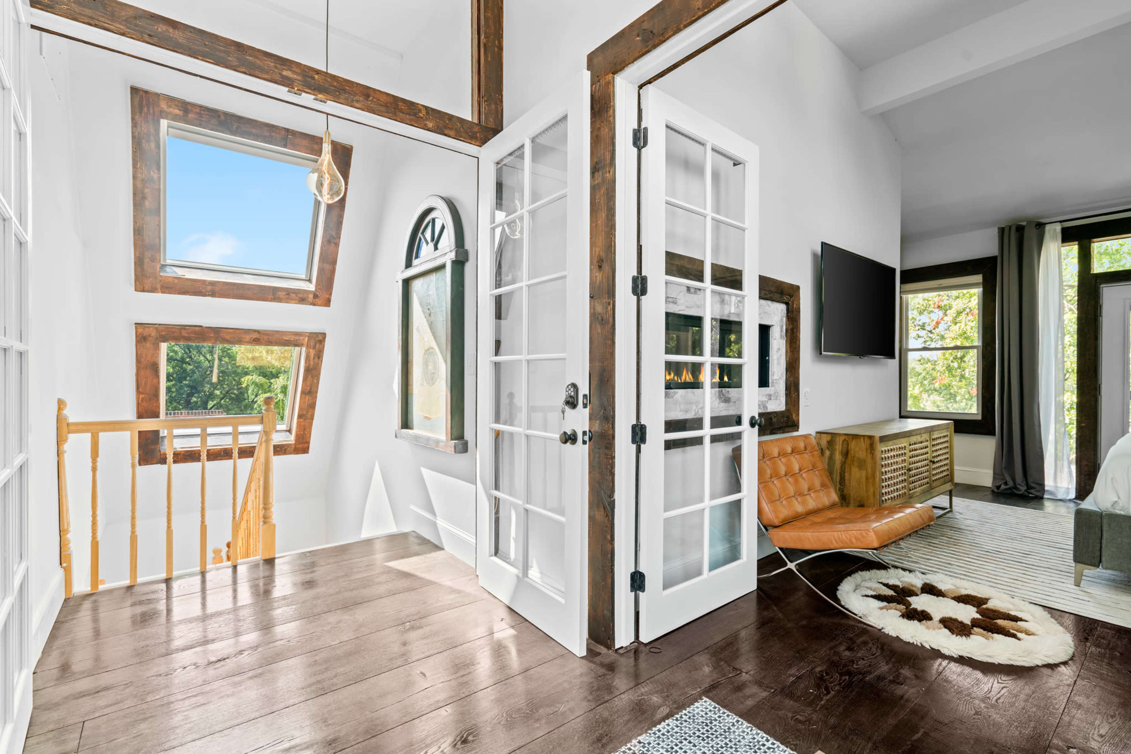 A bright, modern interior with large windows and a stylish staircase leading to a second floor.