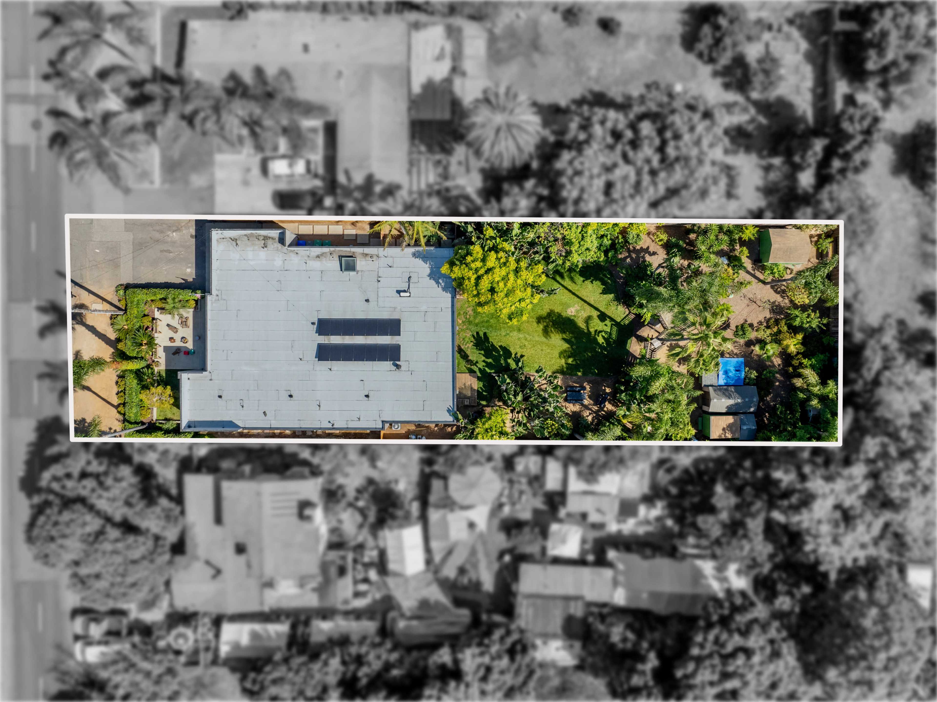 An aerial view of a large building surrounded by a garden and trees, with surrounding residential structures visible.