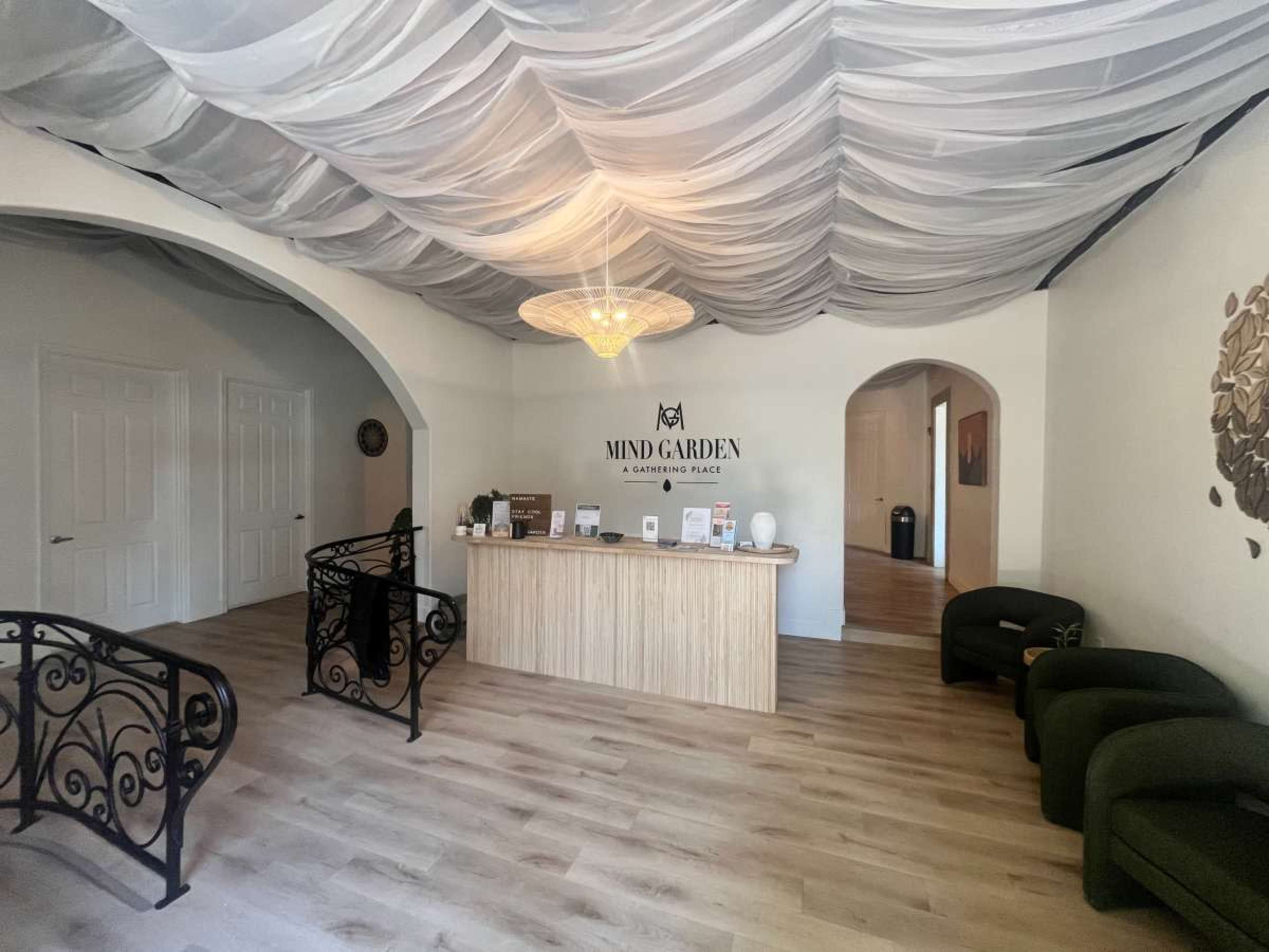 A reception area with a wooden front desk, upholstered seating, and a decorative ceiling draped with fabric.
