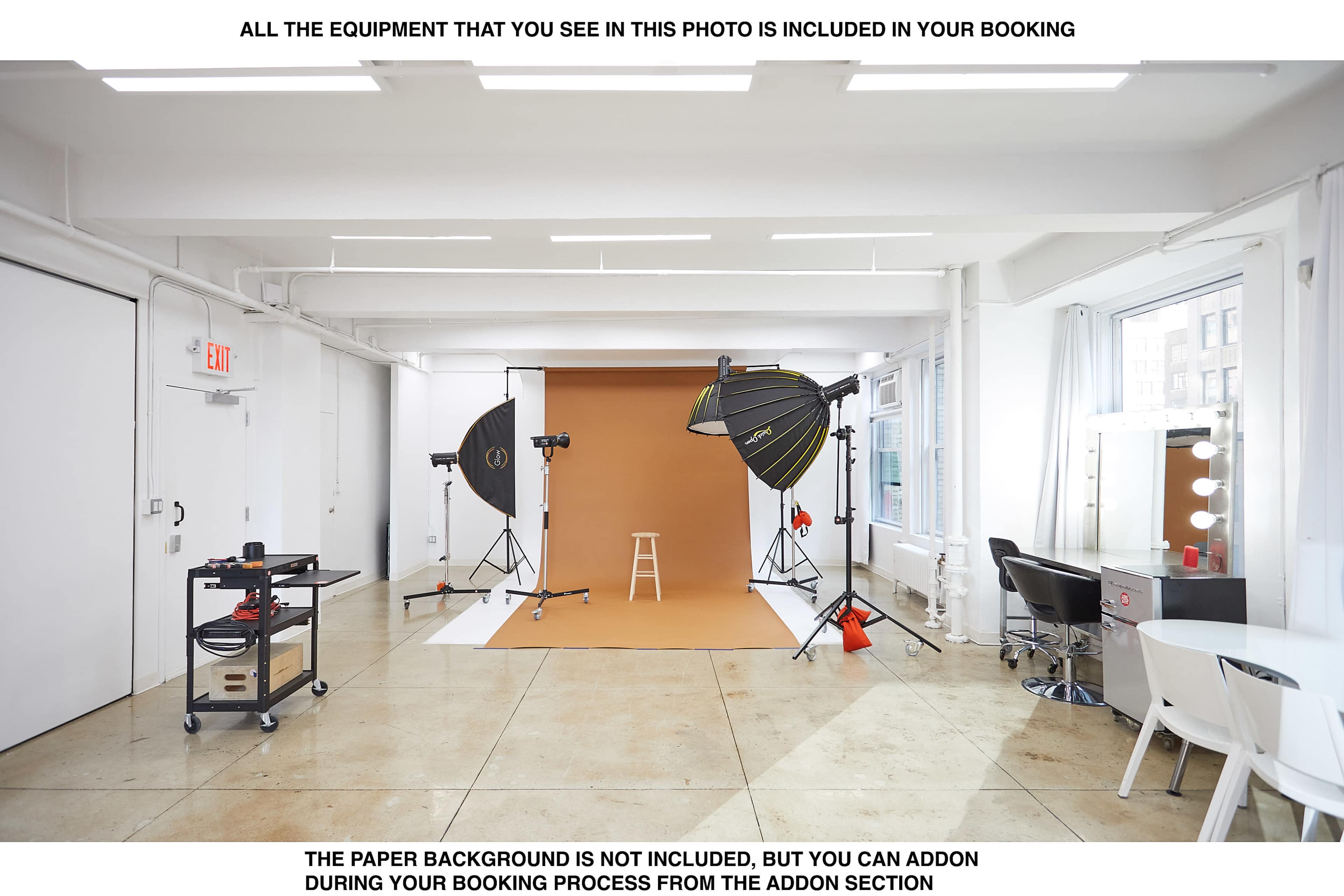 The image shows a photo studio with a brown backdrop, lighting equipment, a makeup station, and polished concrete floors.