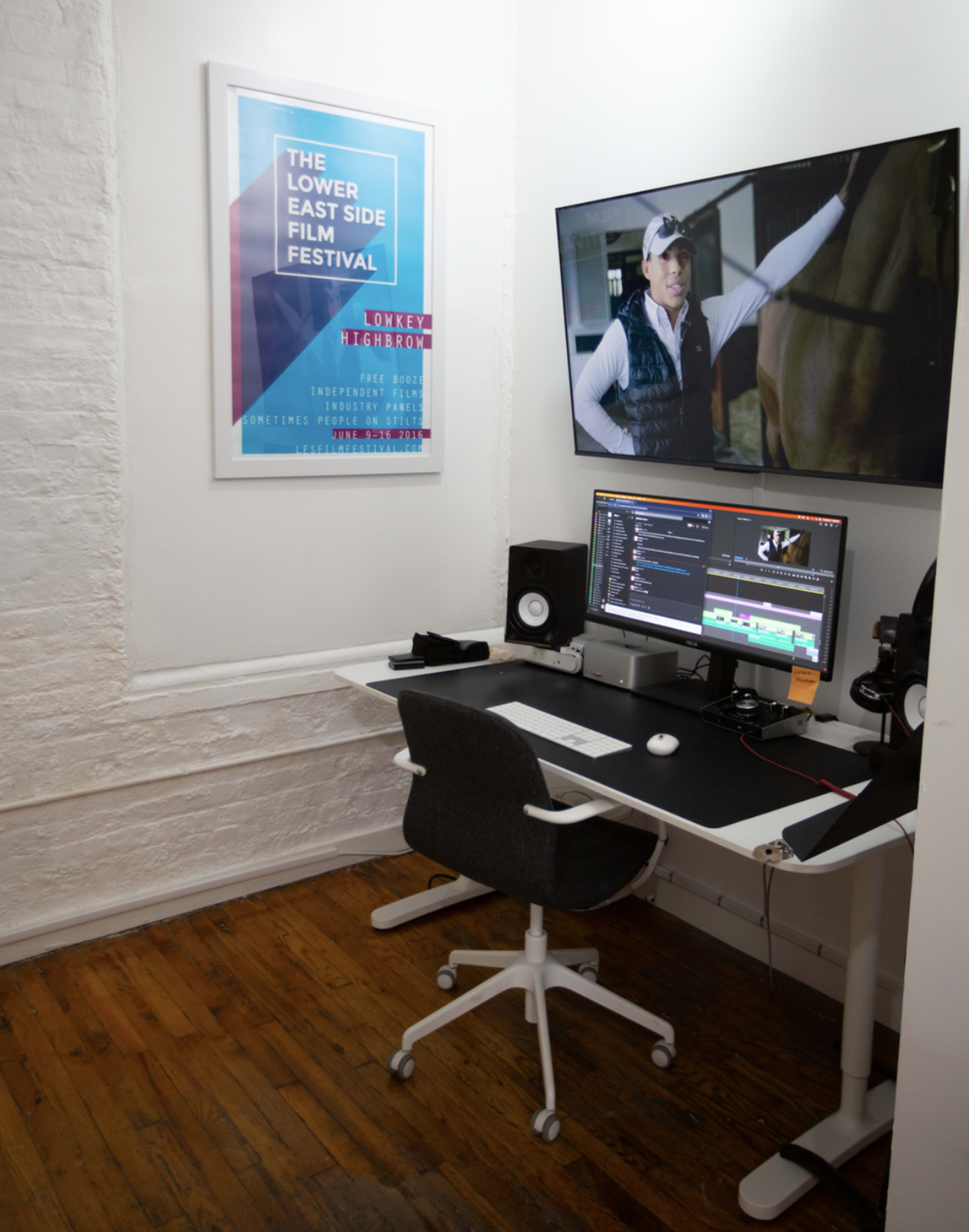 A small workspace features a computer desk with an editing monitor, speakers, and a movie poster hanging on the wall.