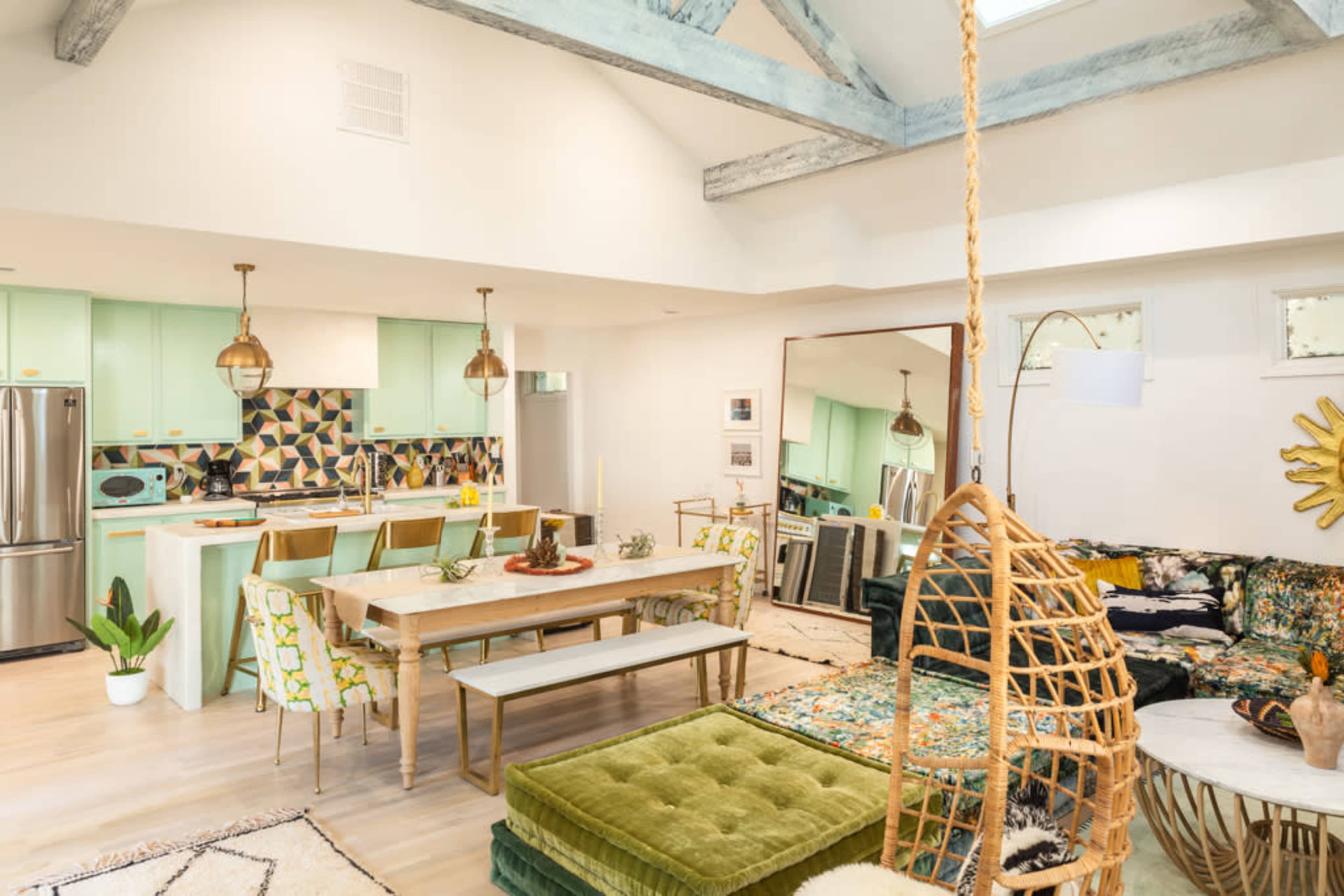 A modern living space with a kitchen, dining area, and a seating area featuring vibrant decor and a mix of seating options.