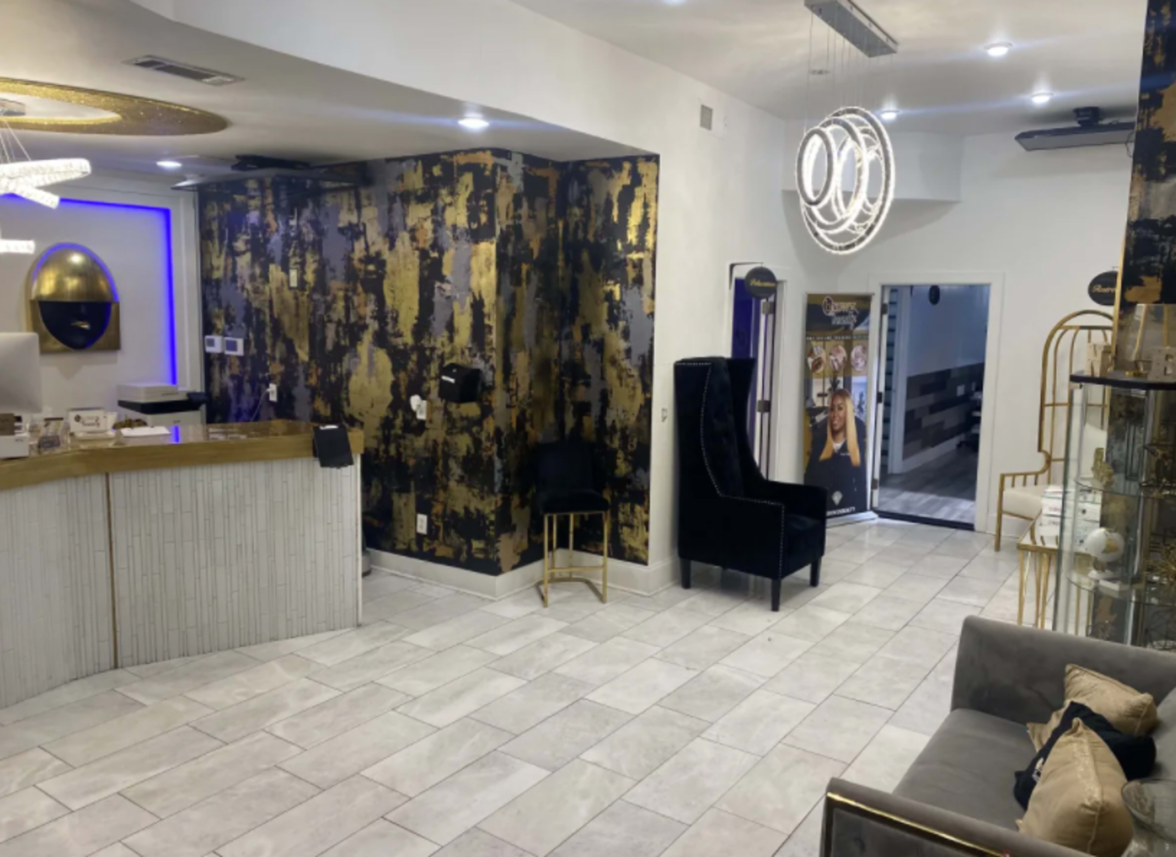 The image shows a modern reception area with a gold and black accent wall, a sleek front desk, and contemporary furnishings.