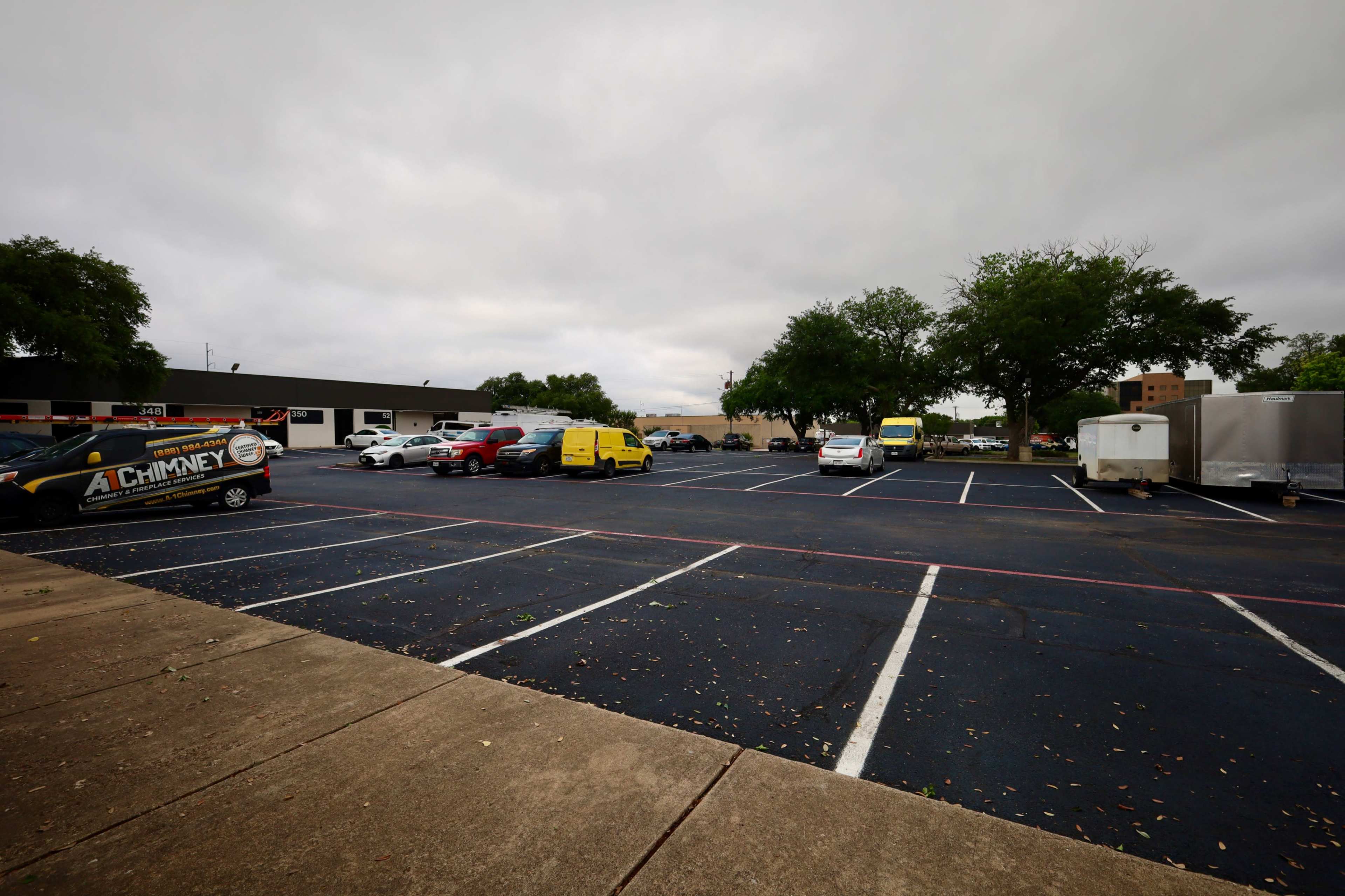 The image shows a parking lot with several vehicles, including cars and vans, under an overcast sky.