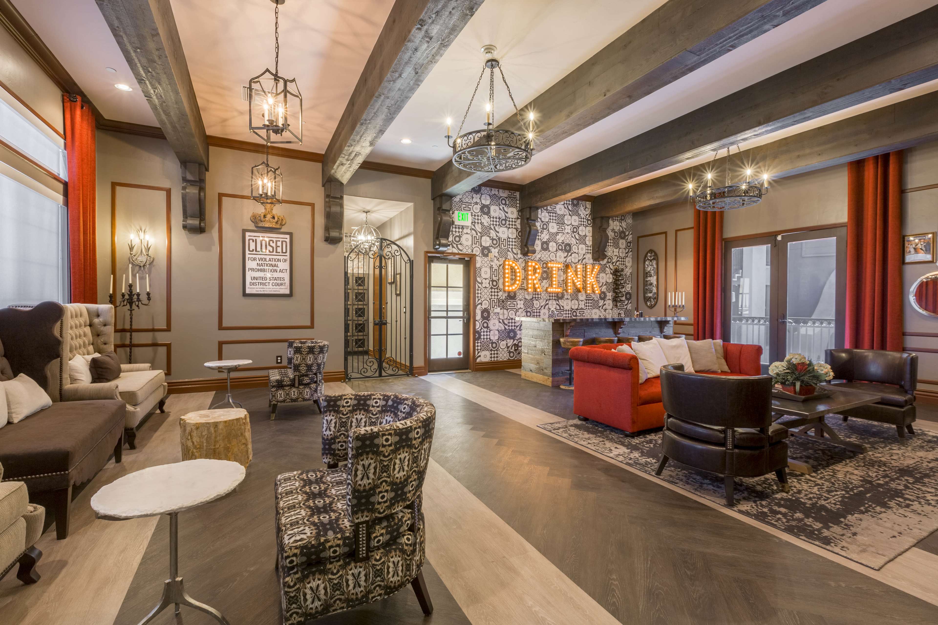 A cozy lounge features a mix of seating arrangements, rustic decor, and illuminated signage reading "DRINK."