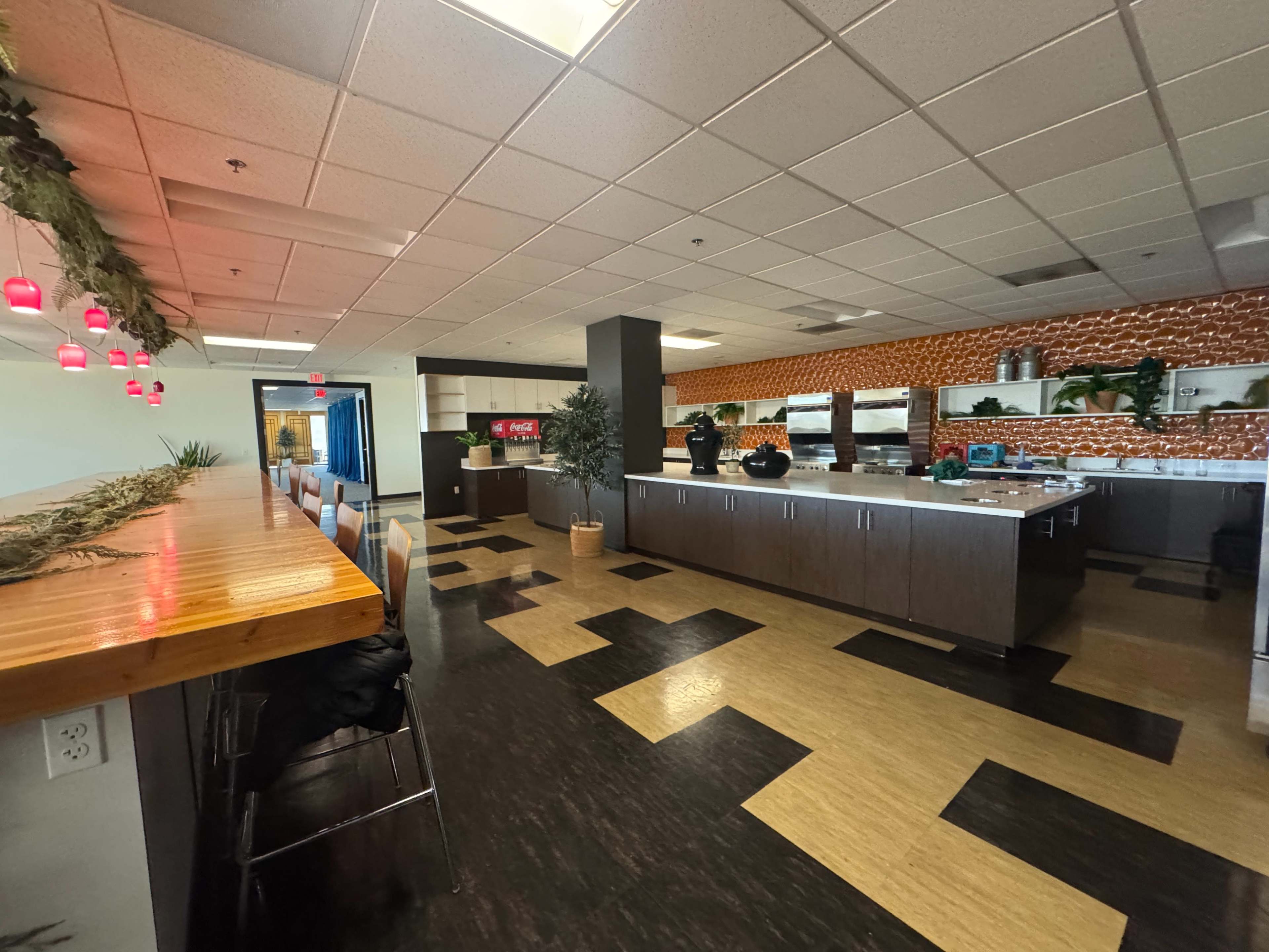 The image shows a modern kitchen with dark cabinets, an island countertop, and seating along the side, illuminated by soft lighting.