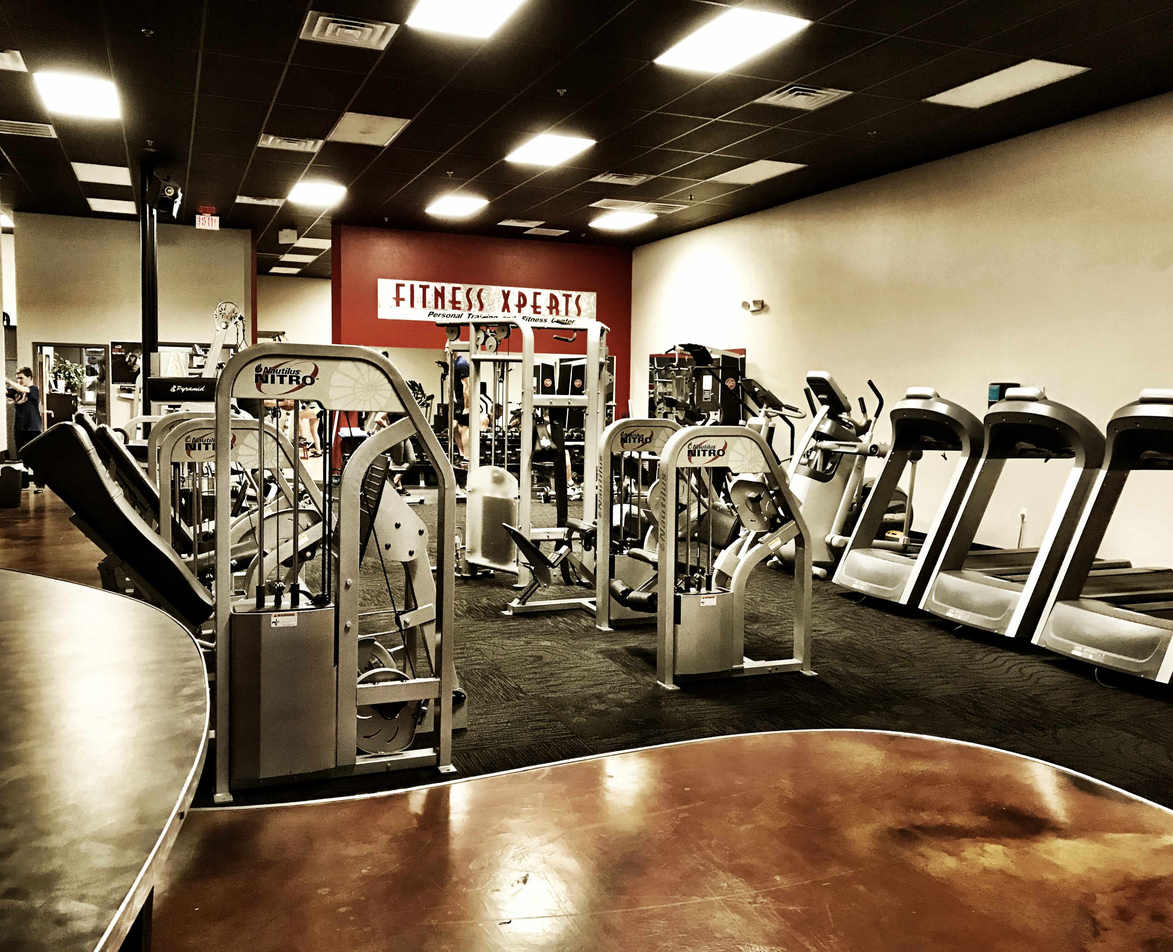 A gym interior with various fitness equipment, including weight machines and treadmills, arranged neatly in a spacious layout.