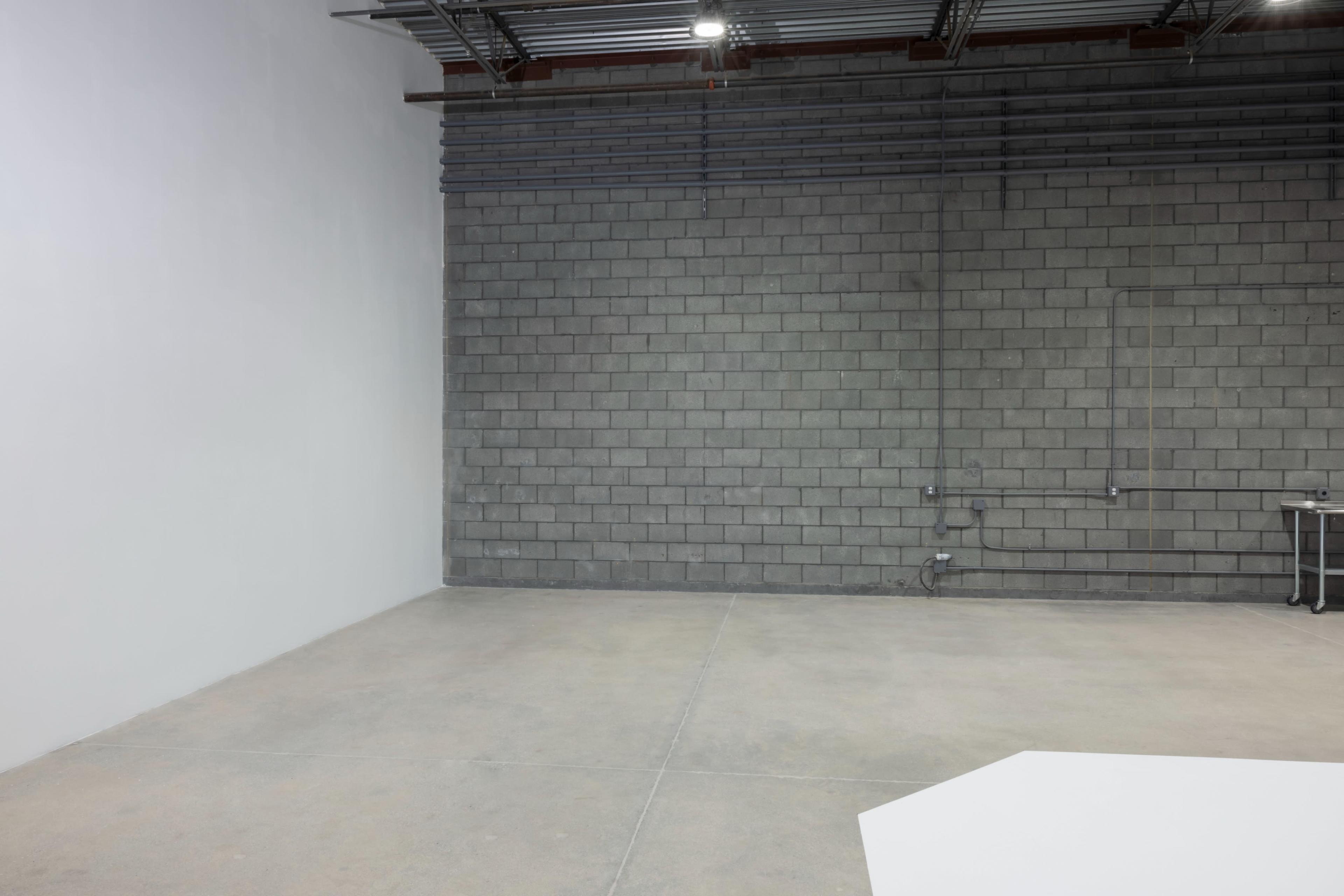 A spacious, empty room with a gray block wall and a smooth concrete floor.