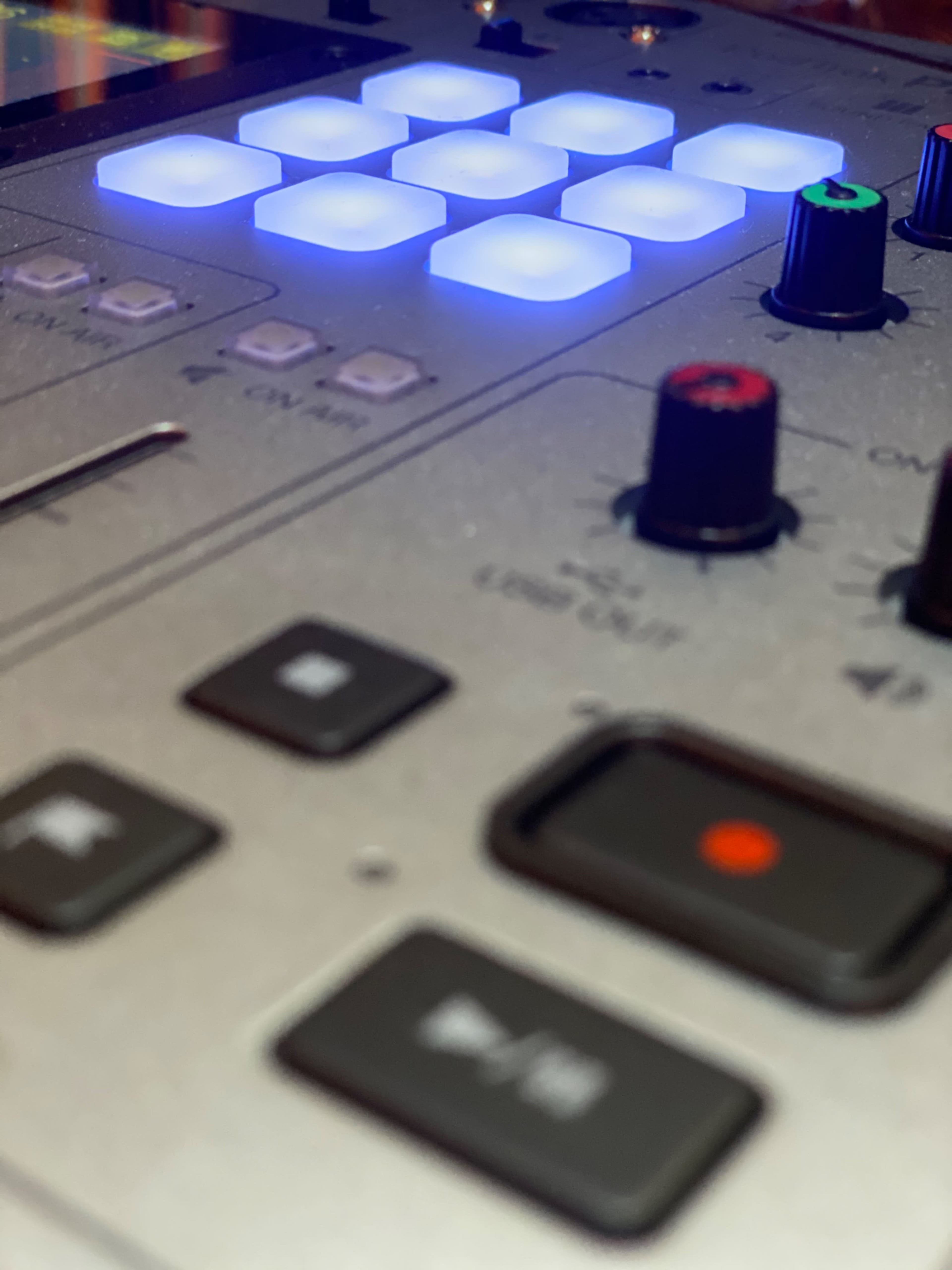A close-up of a mixing console featuring illuminated buttons and knobs.