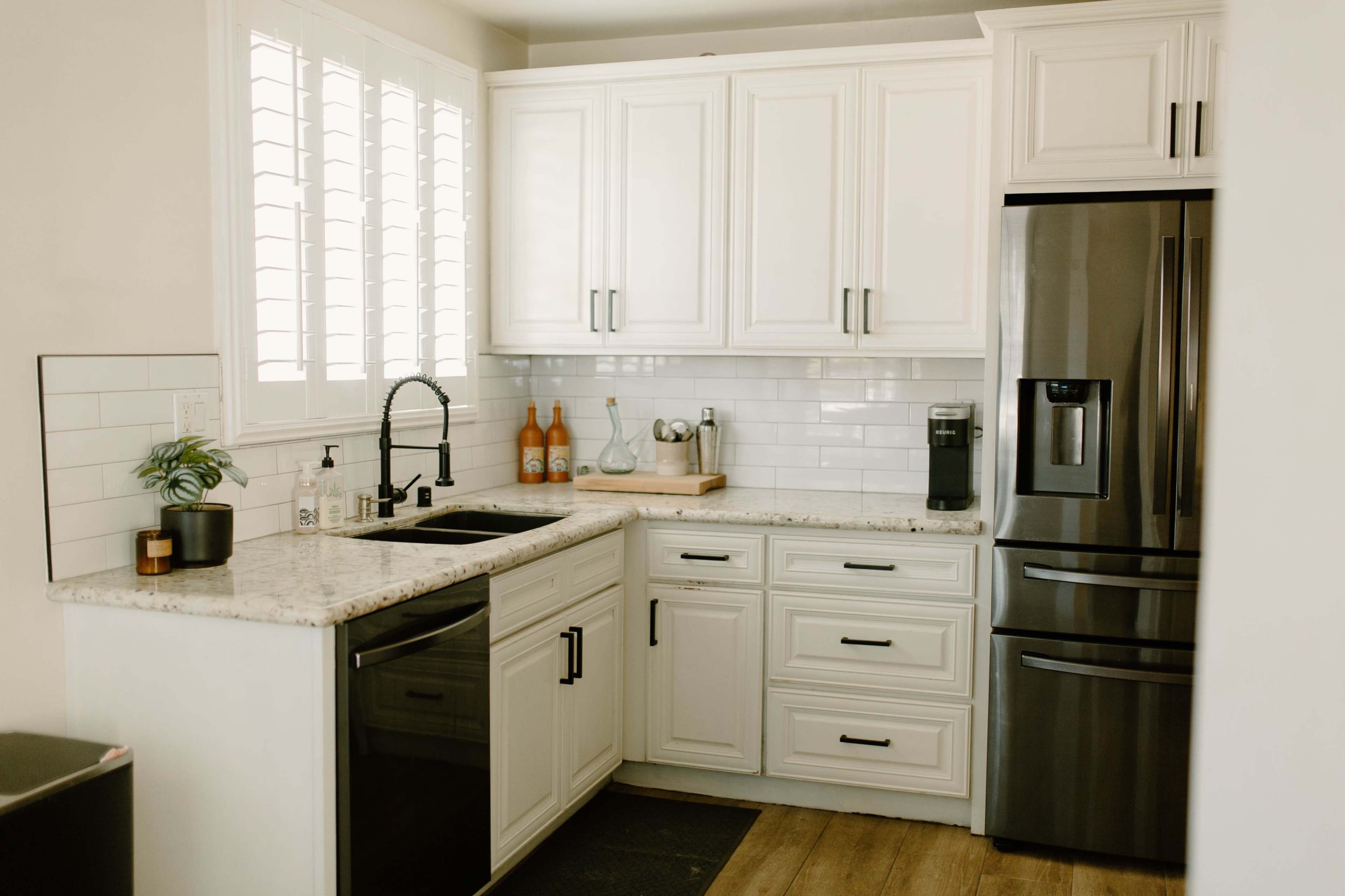 A modern kitchen with white cabinetry, a dark stainless steel refrigerator, and a black sink.