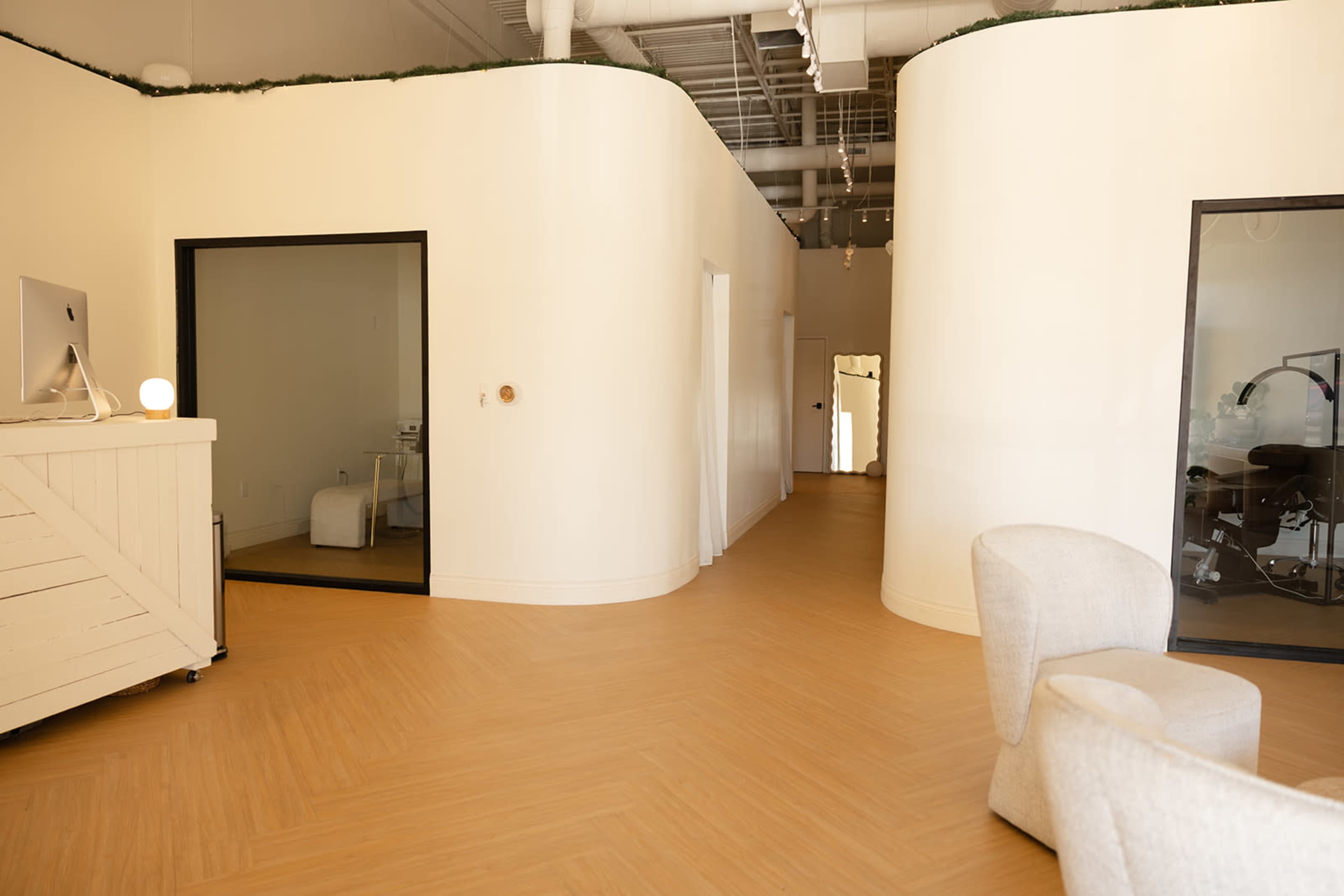 The image shows an interior space featuring a curved wall design, wooden flooring, and several doorways leading to different rooms.