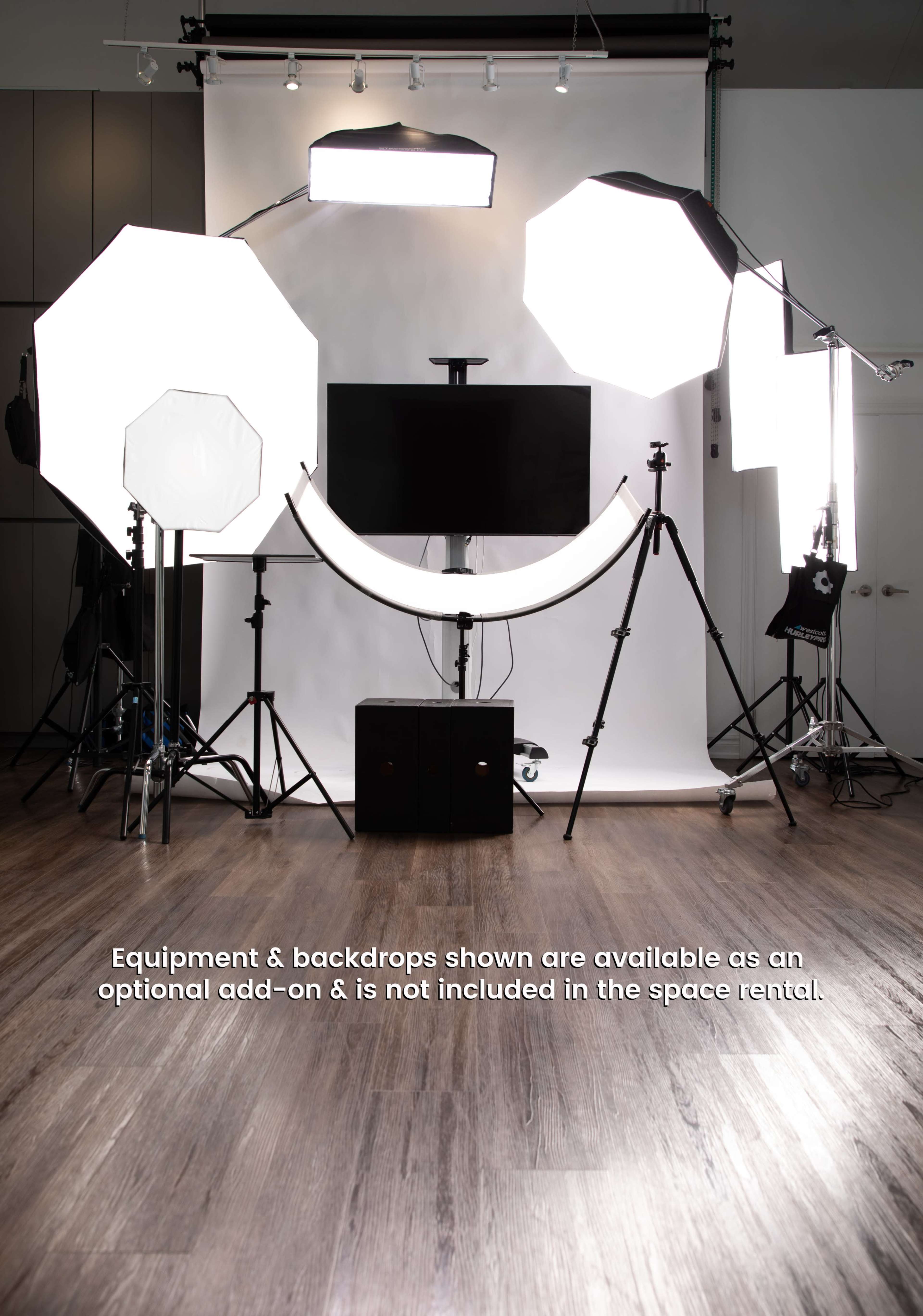 A photography studio is set up with multiple lighting equipment and backdrops arranged around a central display monitor.