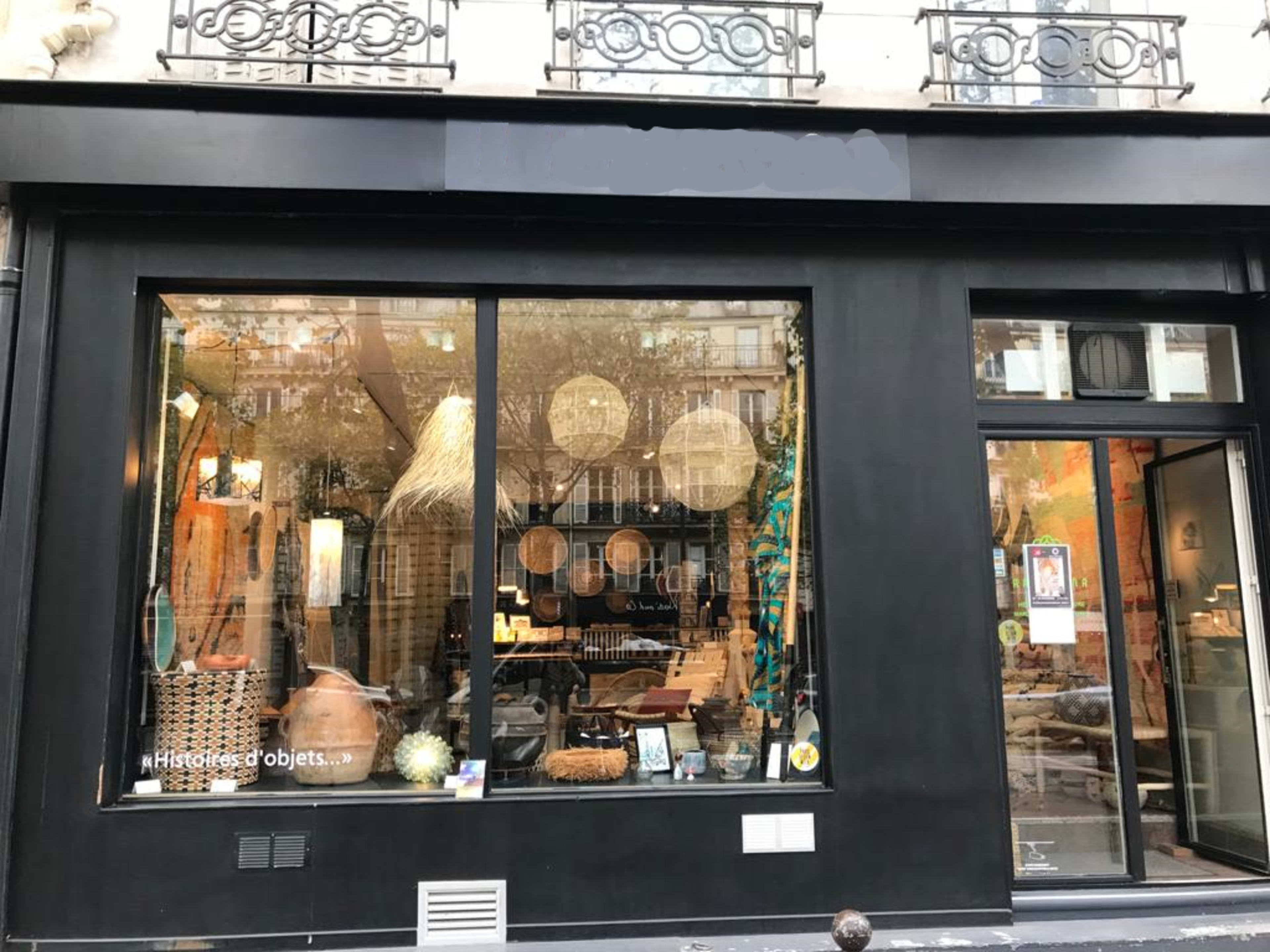 A black storefront displays a large window filled with various decorative items and furniture.