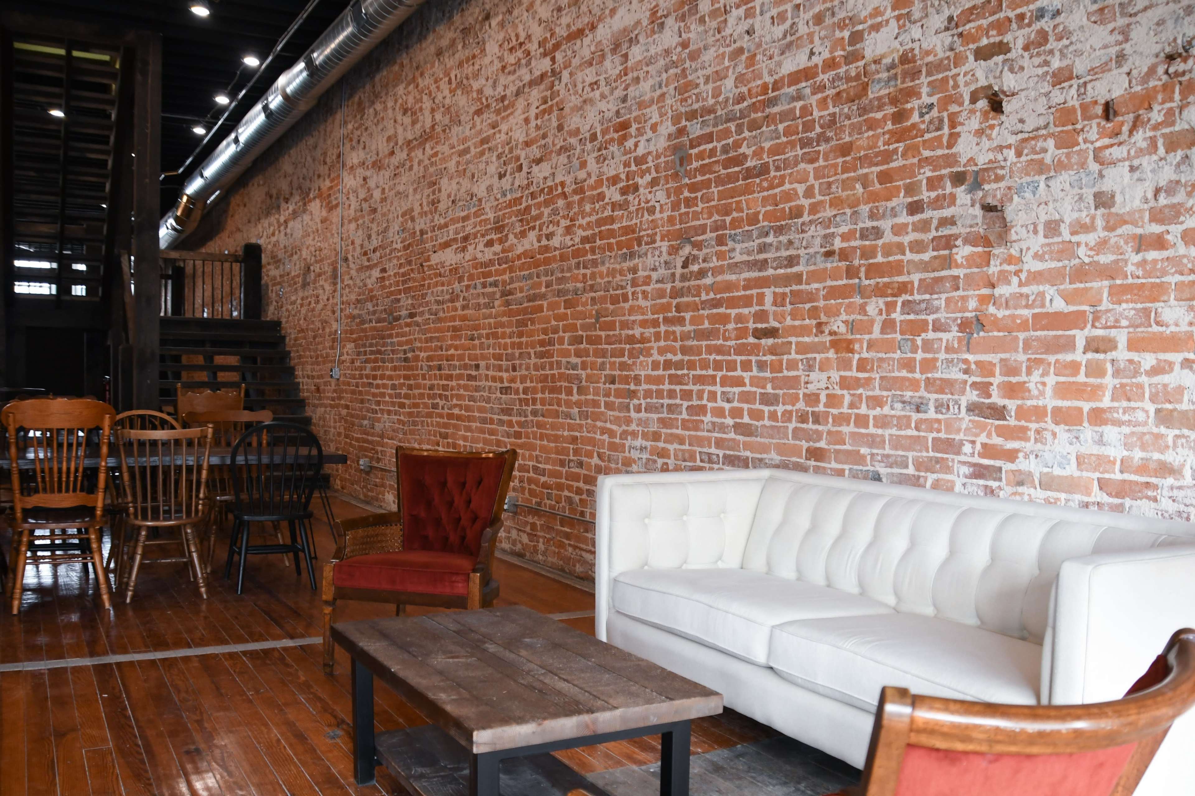 A rustic interior with exposed brick walls, wooden furniture, and a neutral-colored sofa in a cozy seating area.