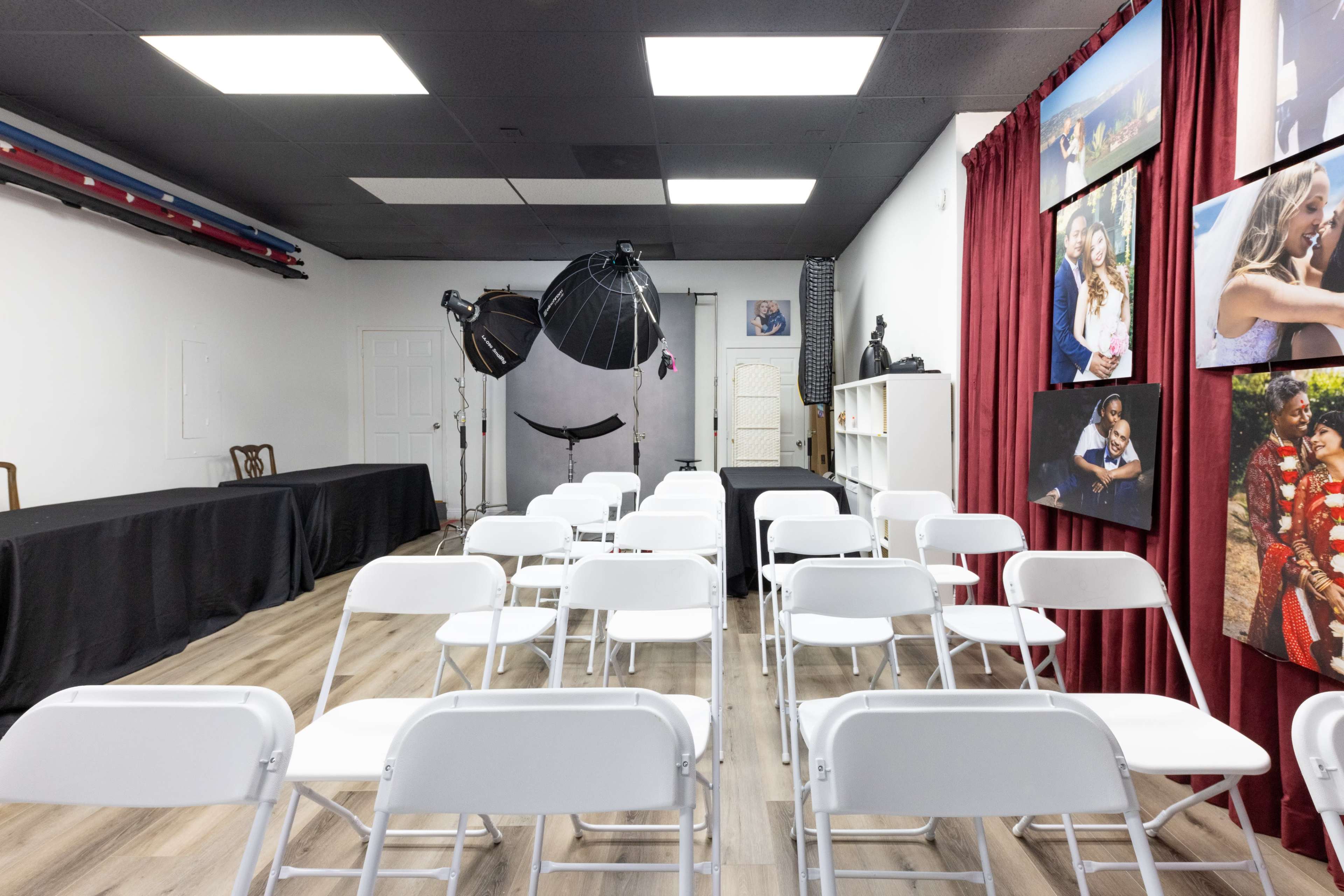 The image shows a photography studio setup with white chairs arranged in rows, a backdrop, and lighting equipment in an indoor space.