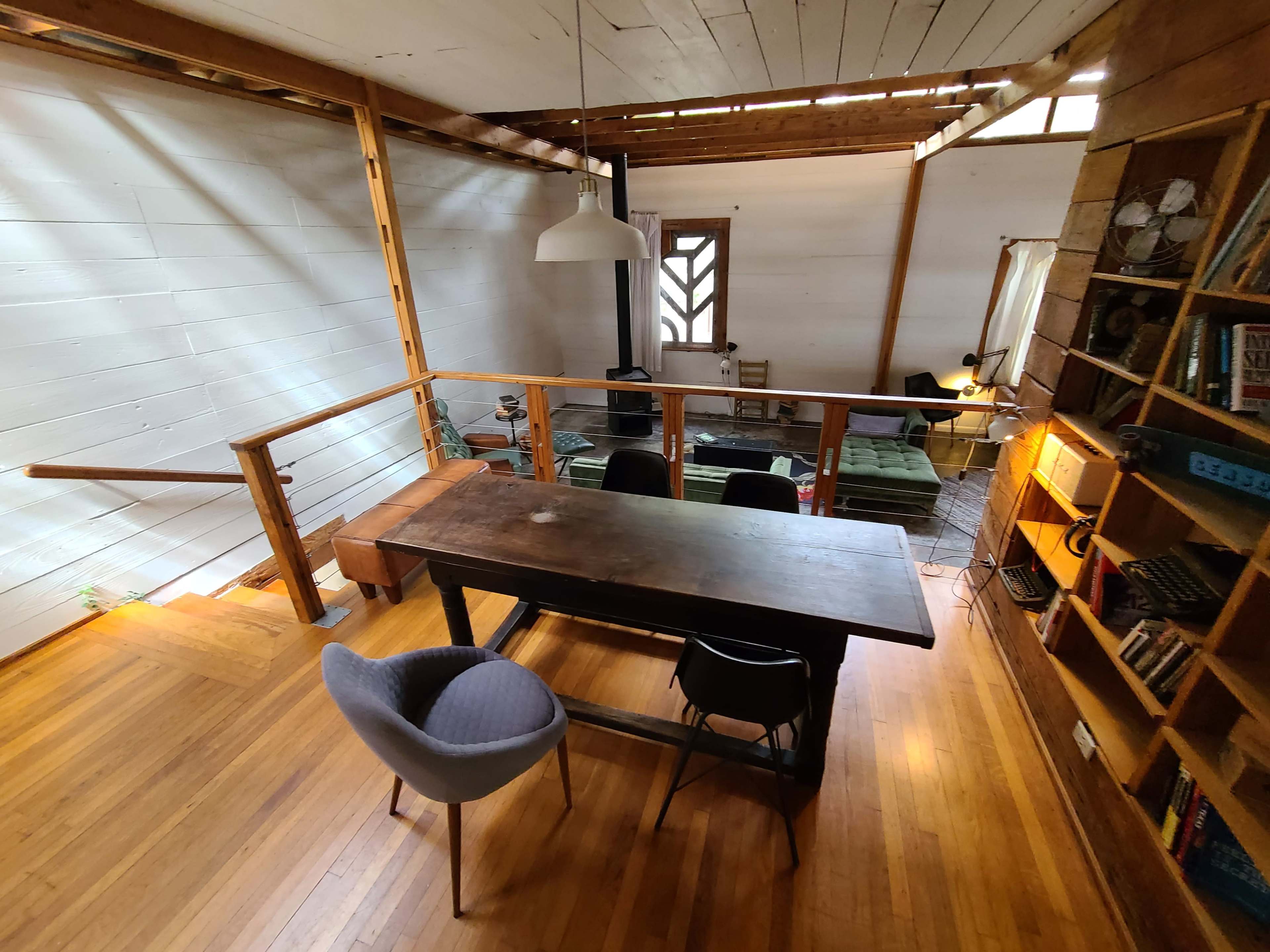 A spacious room features a wooden table with chairs, overlooking a cozy living area illuminated by natural light.