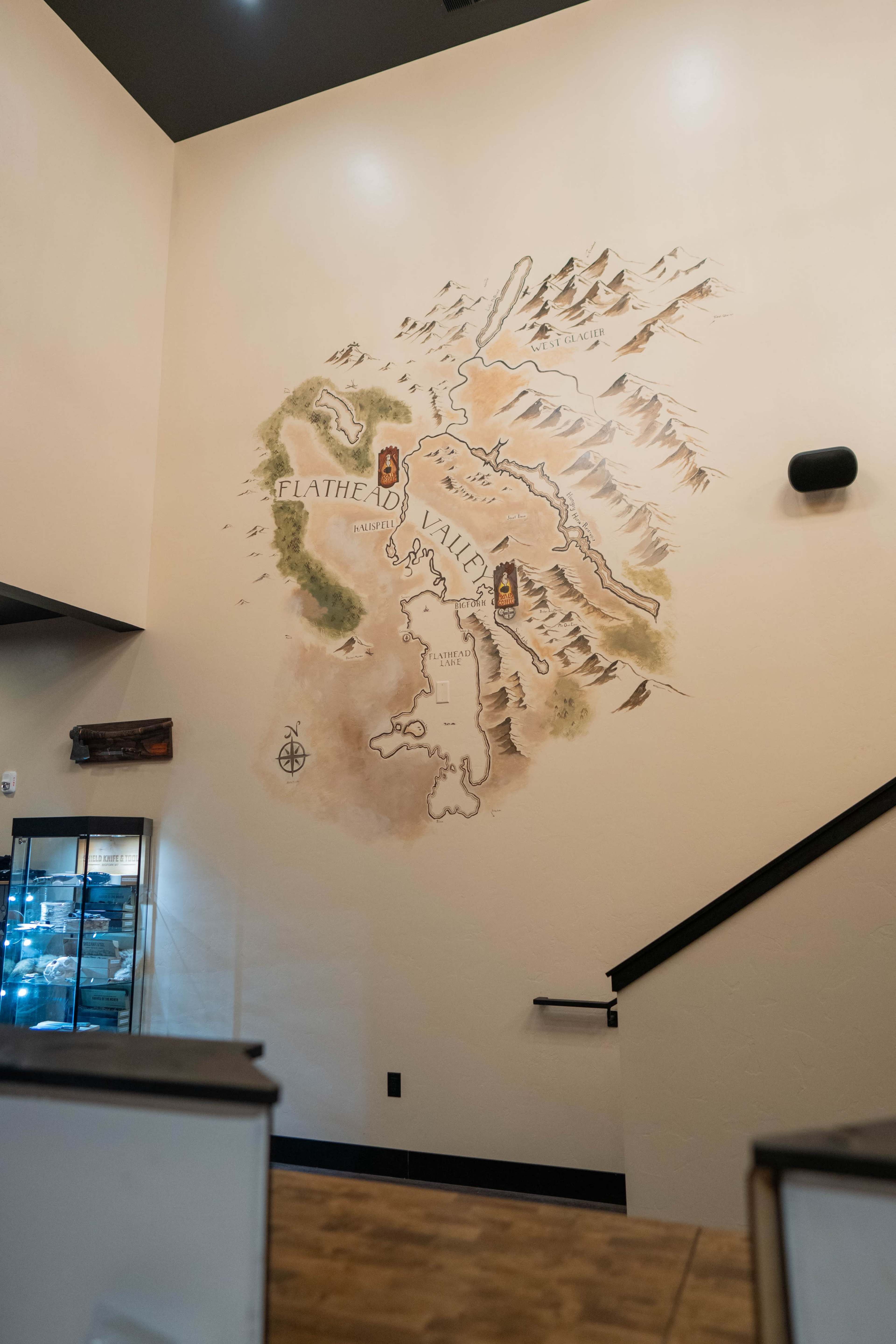The image shows a large mural of a map on a wall, depicting mountains and water bodies, with labels for "Flathead" and "Valley" highlighted in distinct colors.