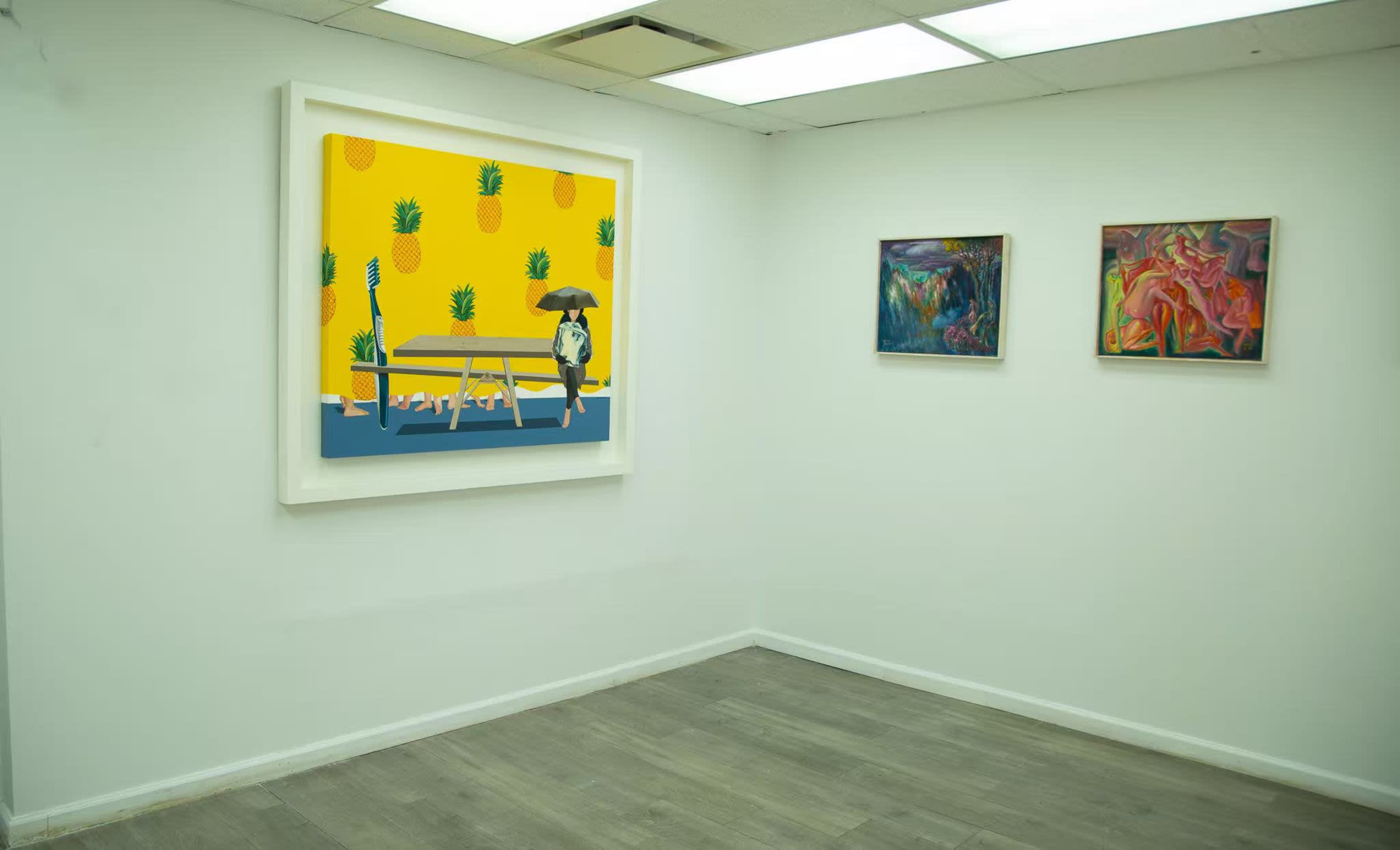 The image shows an art gallery interior featuring a large framed artwork with a dog under an umbrella on a vibrant yellow background, alongside two smaller framed paintings on the right wall.