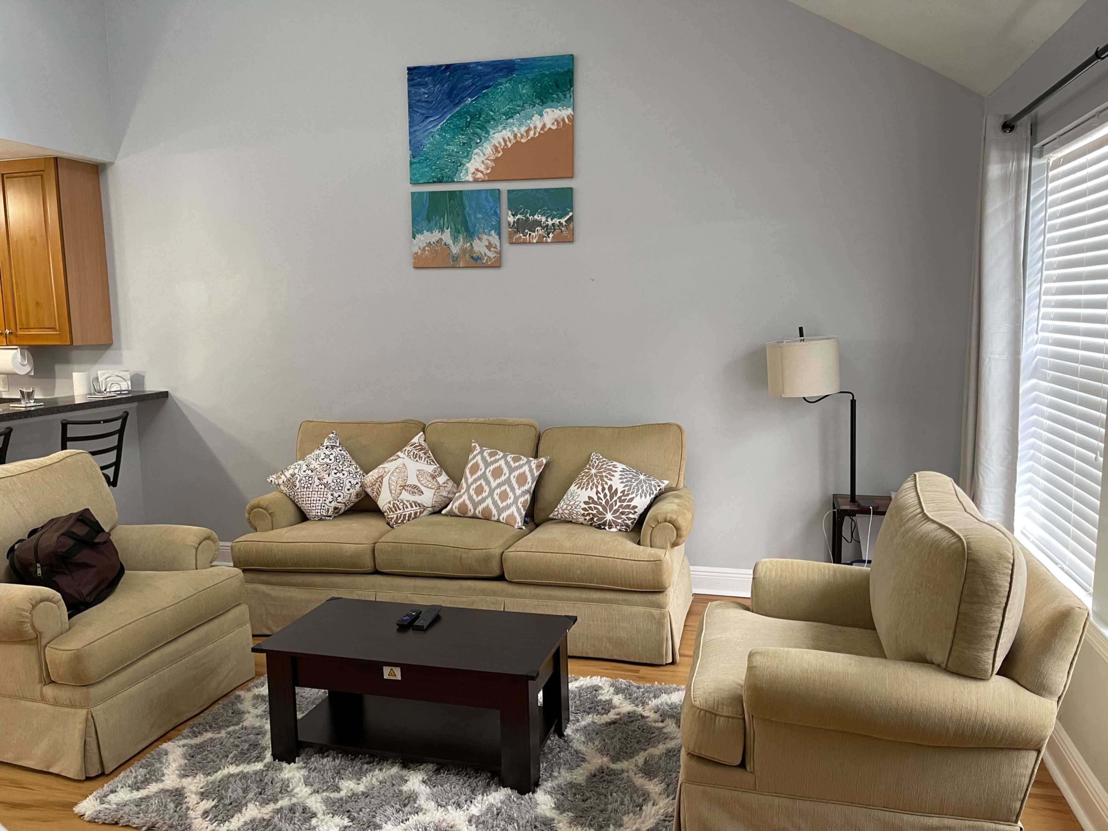 A living room with two sofas, a coffee table, and beach-themed artwork on the wall.