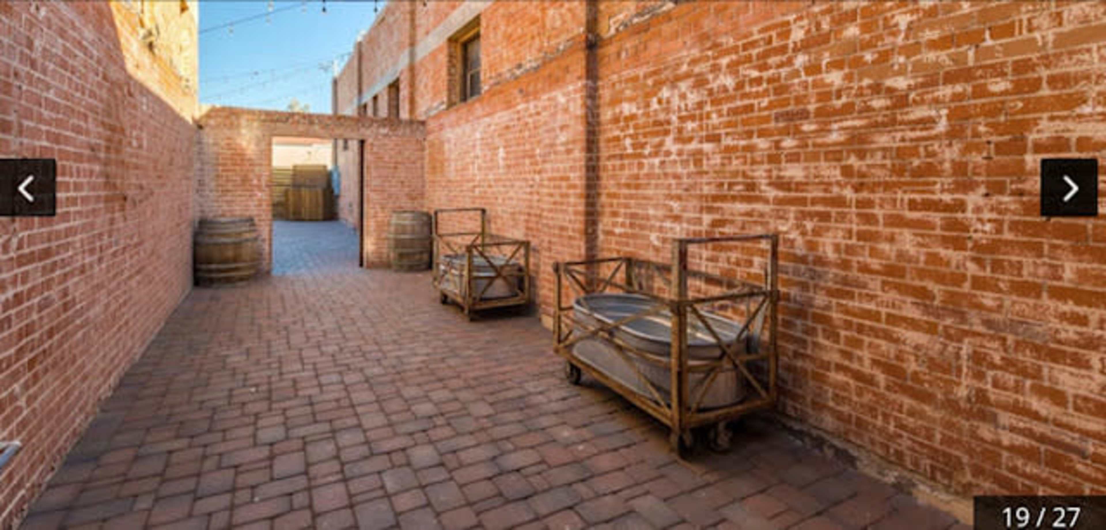 A brick-paved alleyway lined with brick walls and two wooden carts on wheels.