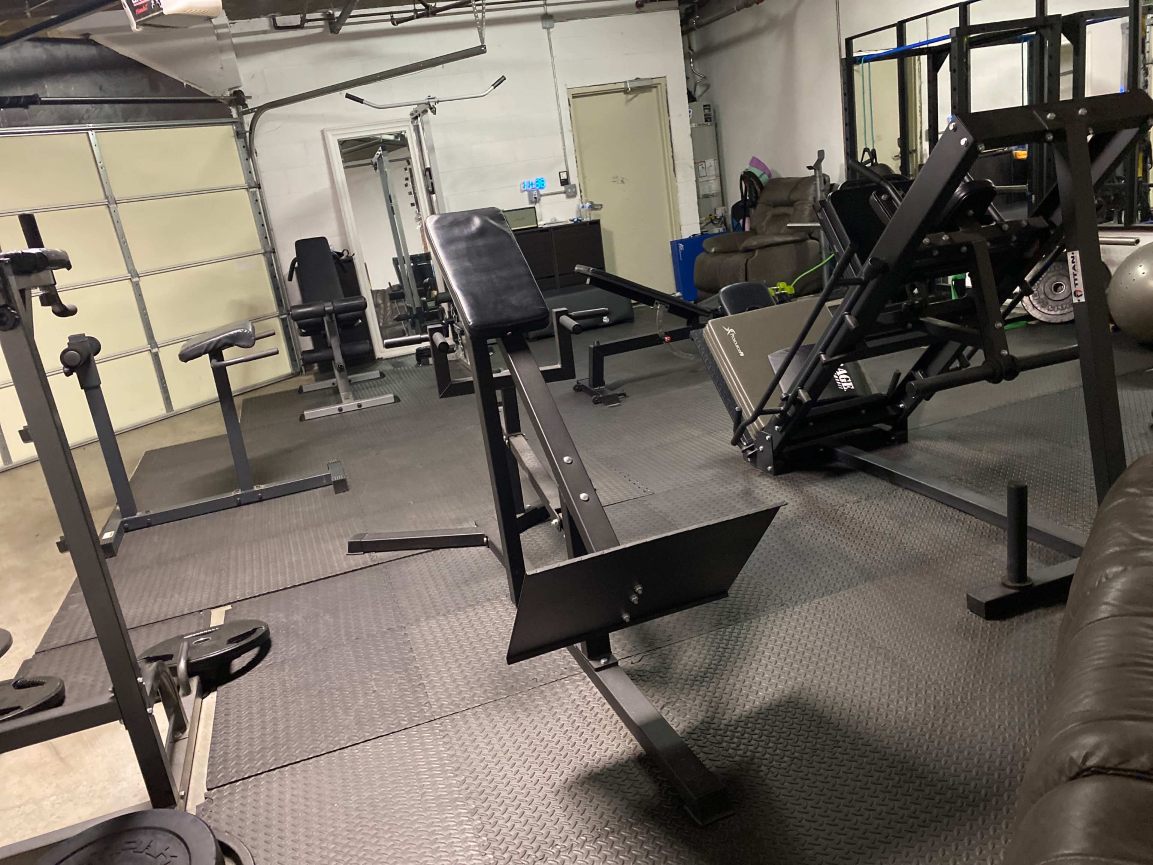 A workout space with various gym equipment, including benches and weights, arranged on a rubber mat floor.