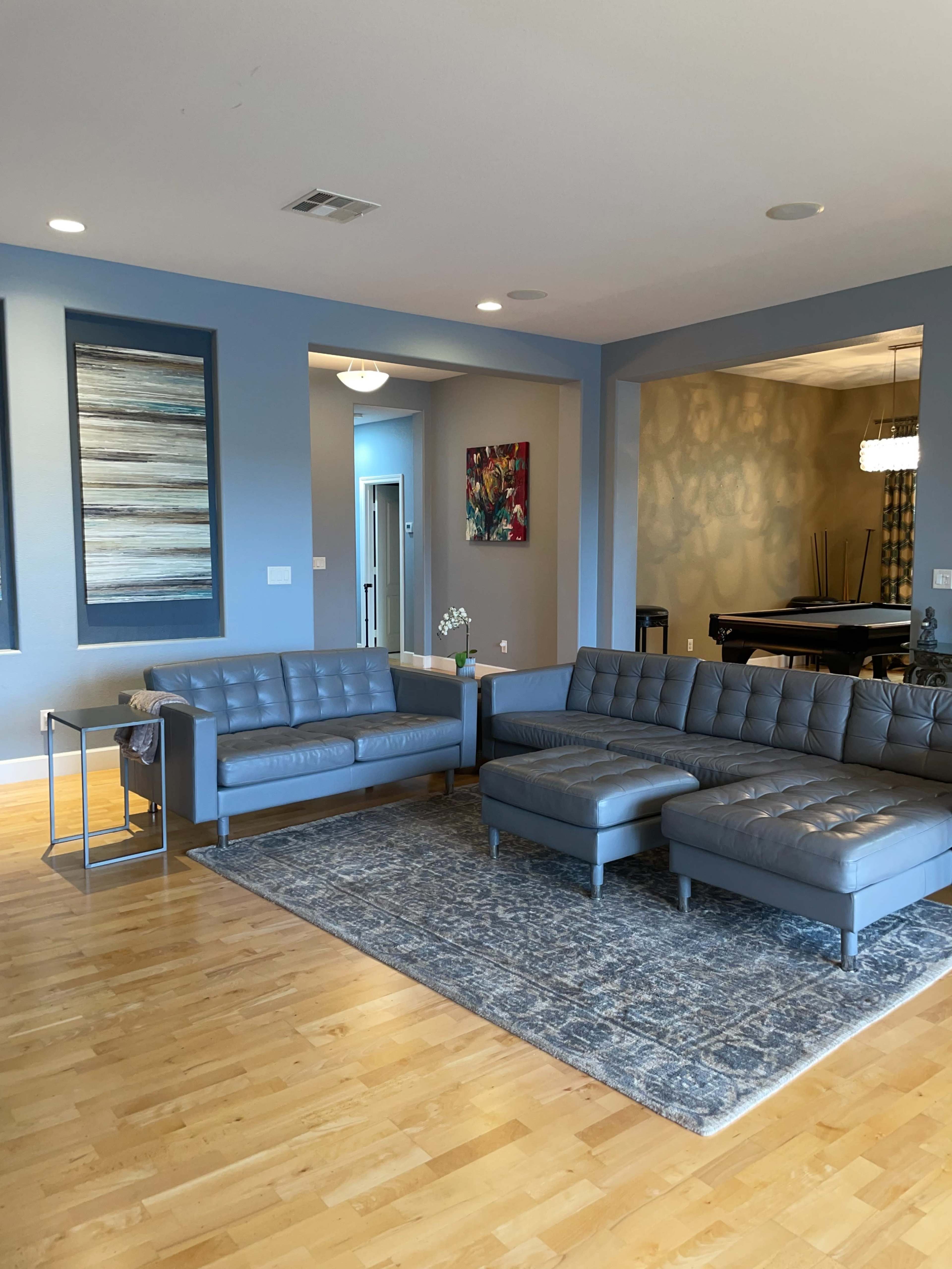 The living room features a gray sectional sofa, a matching loveseat, and a patterned area rug on light wooden flooring.