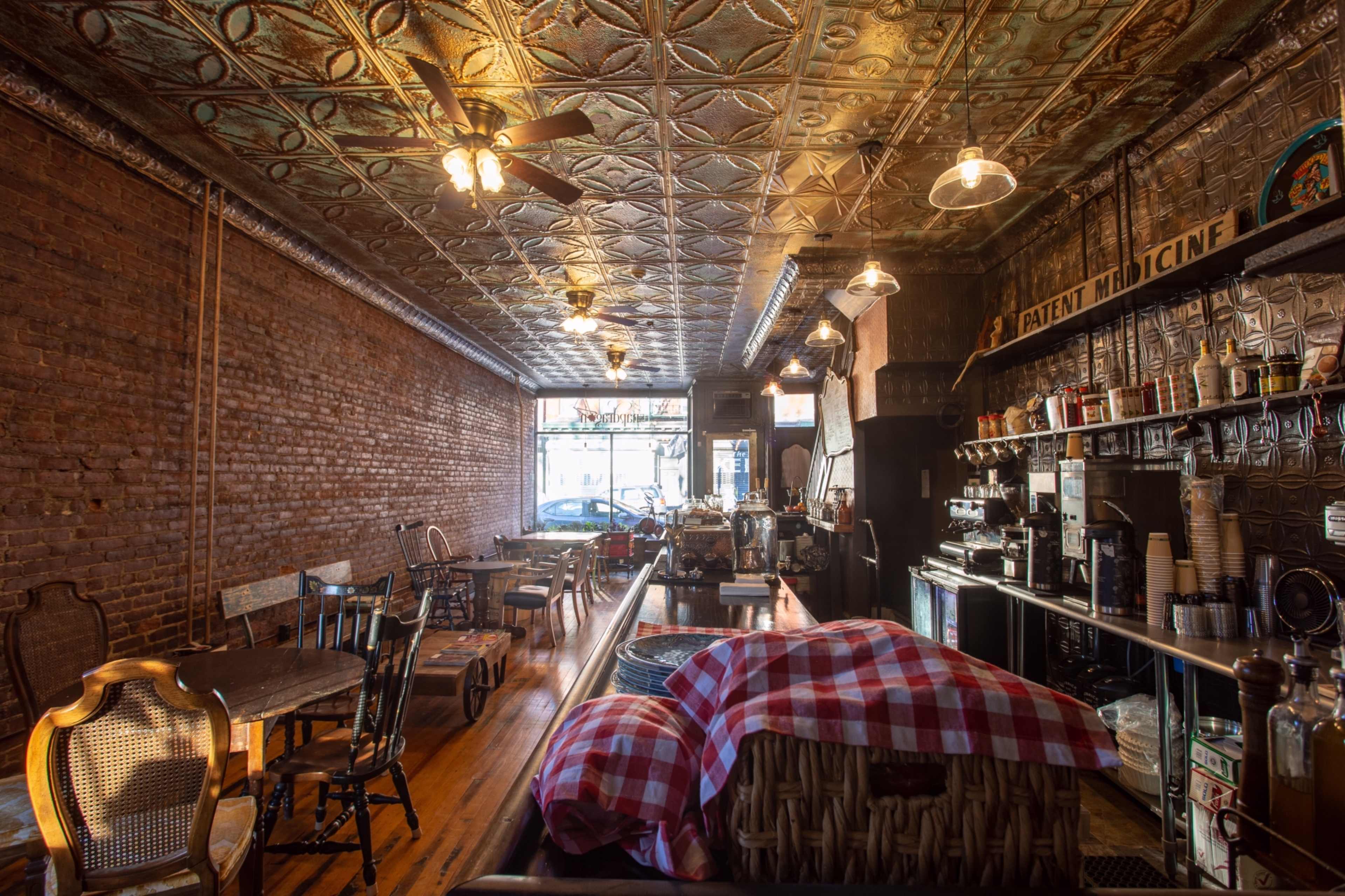 An empty rustic café with exposed brick walls, wooden flooring, and a variety of seating arrangements.