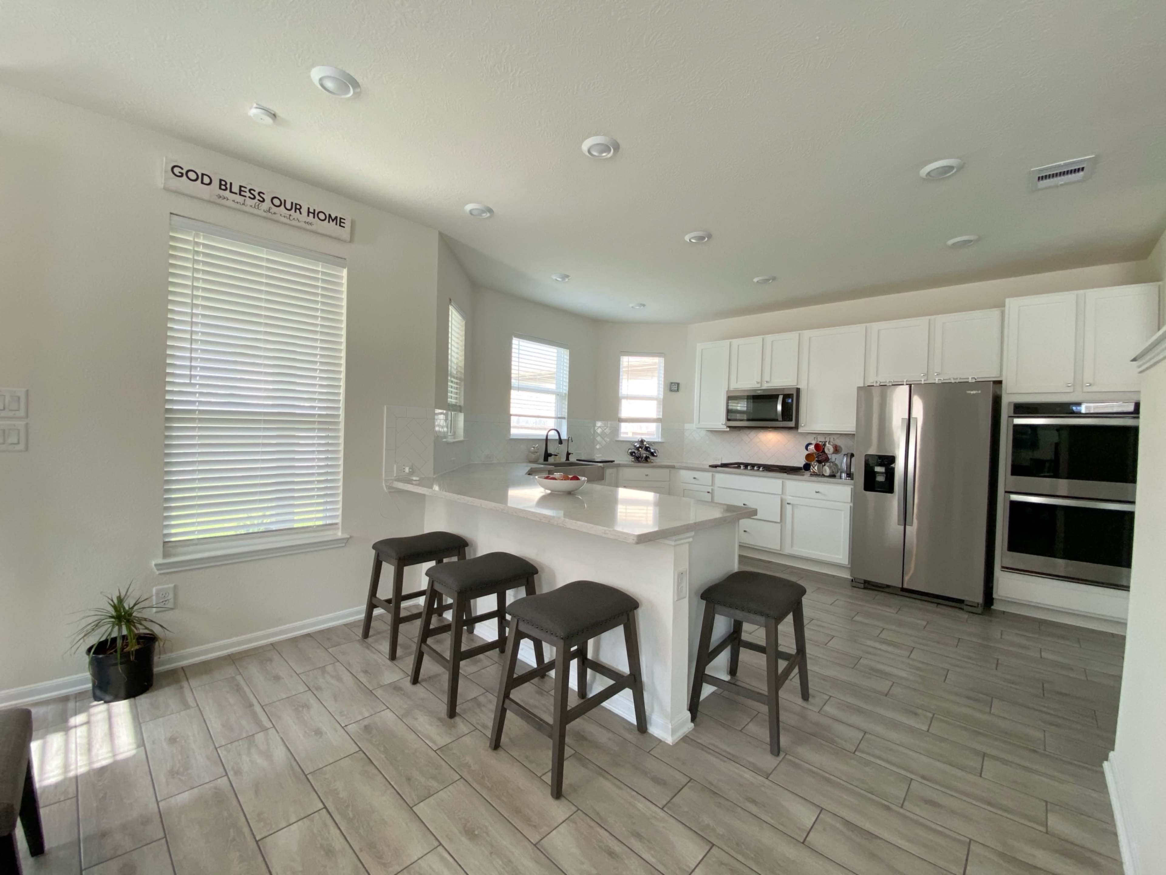 A modern kitchen with white cabinets, a central island with seating, and stainless steel appliances.