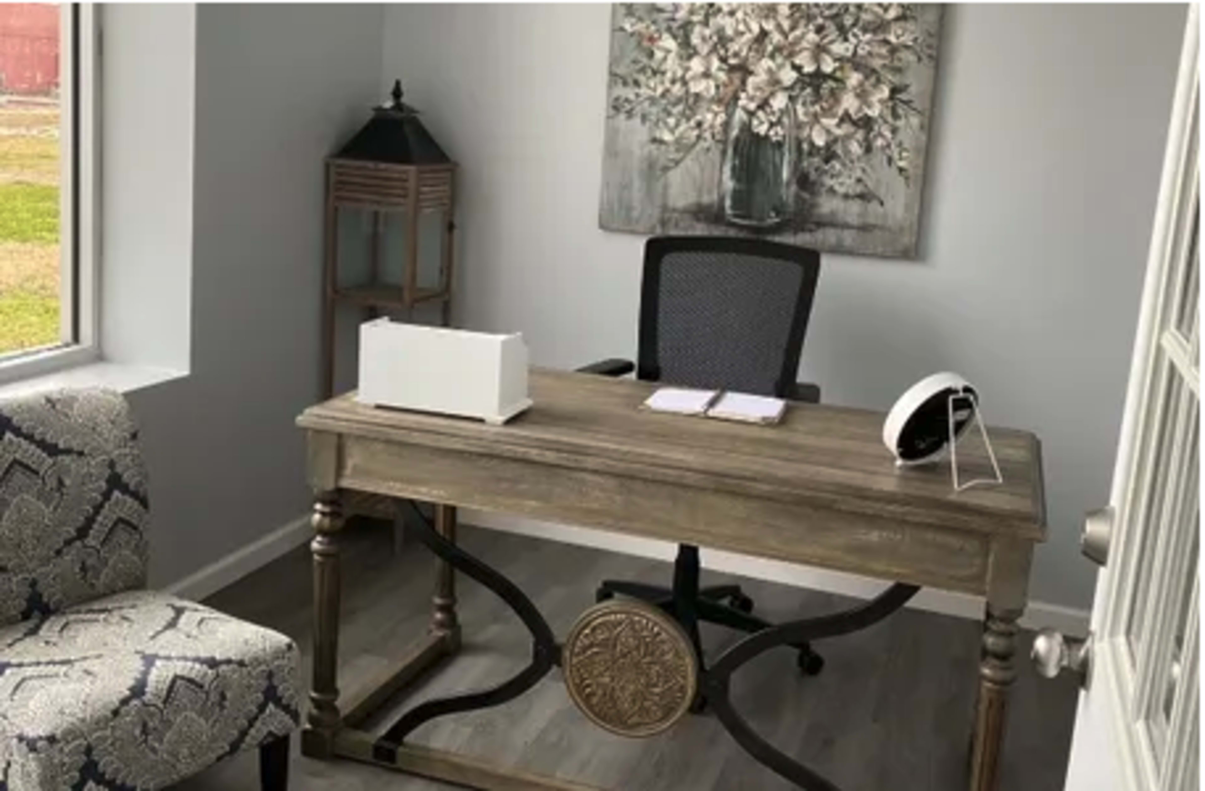 A minimalist office space featuring a wooden desk, a black office chair, and a floral wall art.