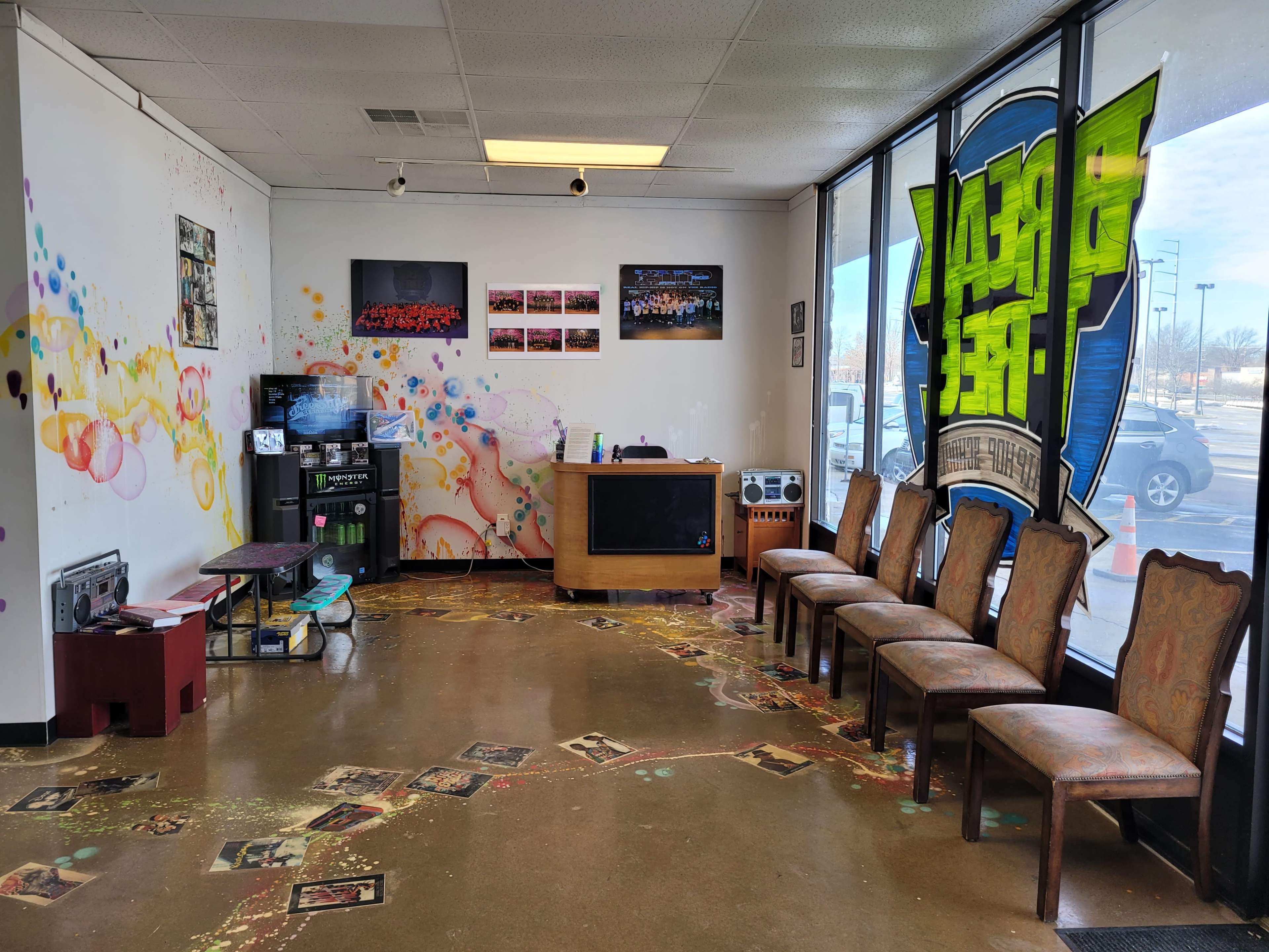 A colorful, empty waiting area with chairs along one wall, a reception desk, and a TV in a corner.