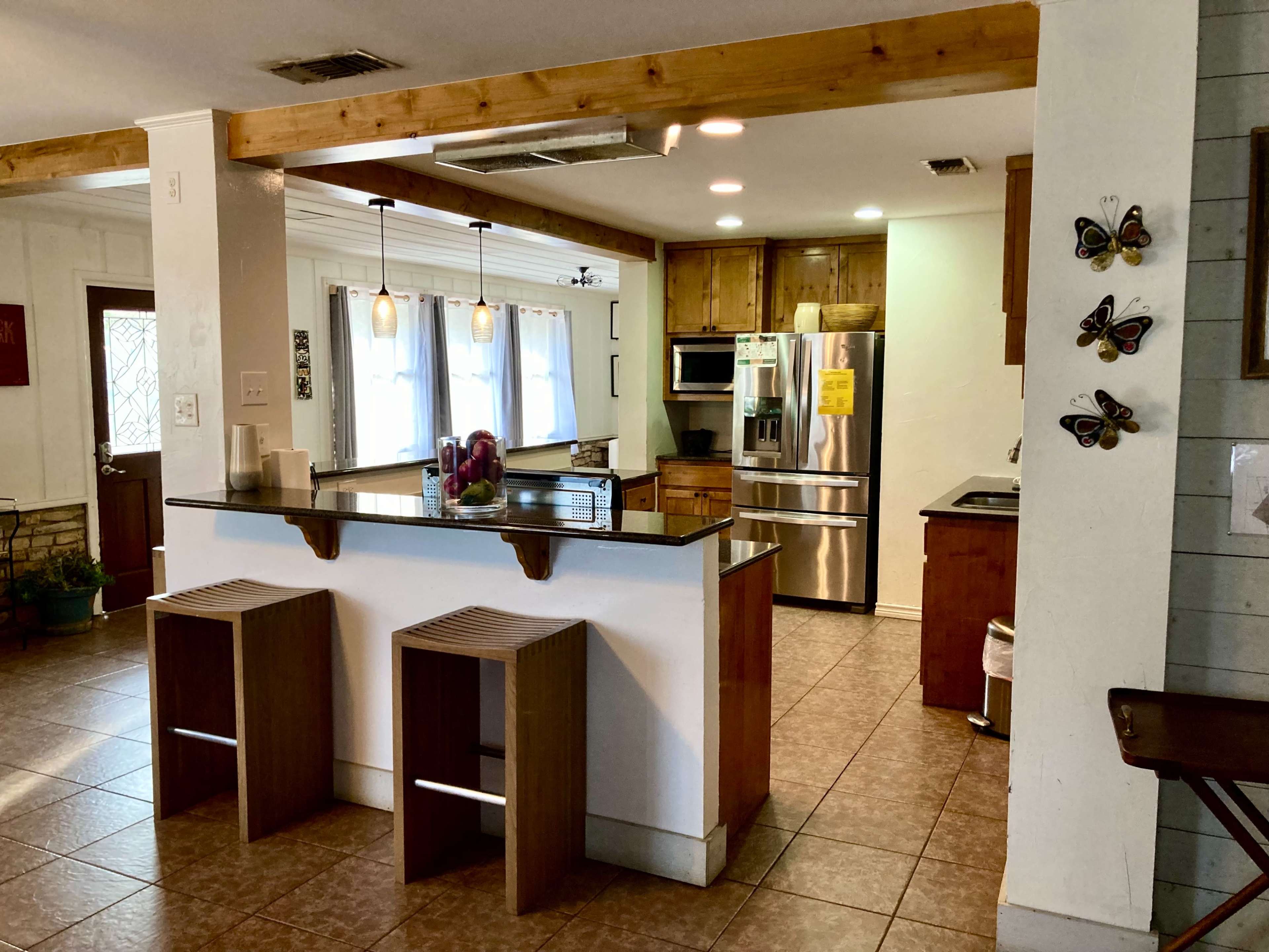 A modern kitchen with a central island, wooden cabinetry, stainless steel appliances, and tiled flooring.