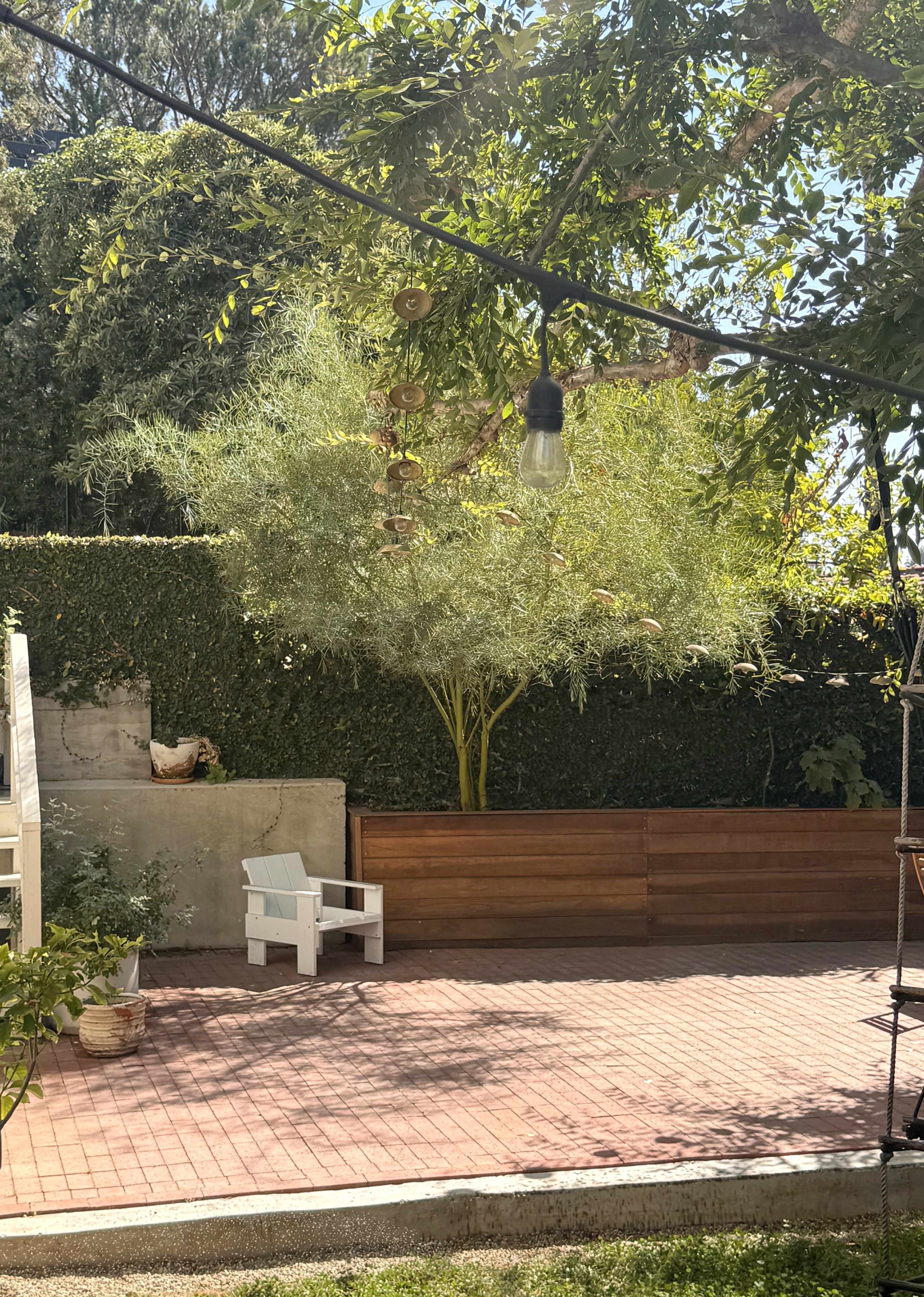 The image shows a peaceful outdoor area with a wooden fence, a white chair, and a lush green tree in the background.