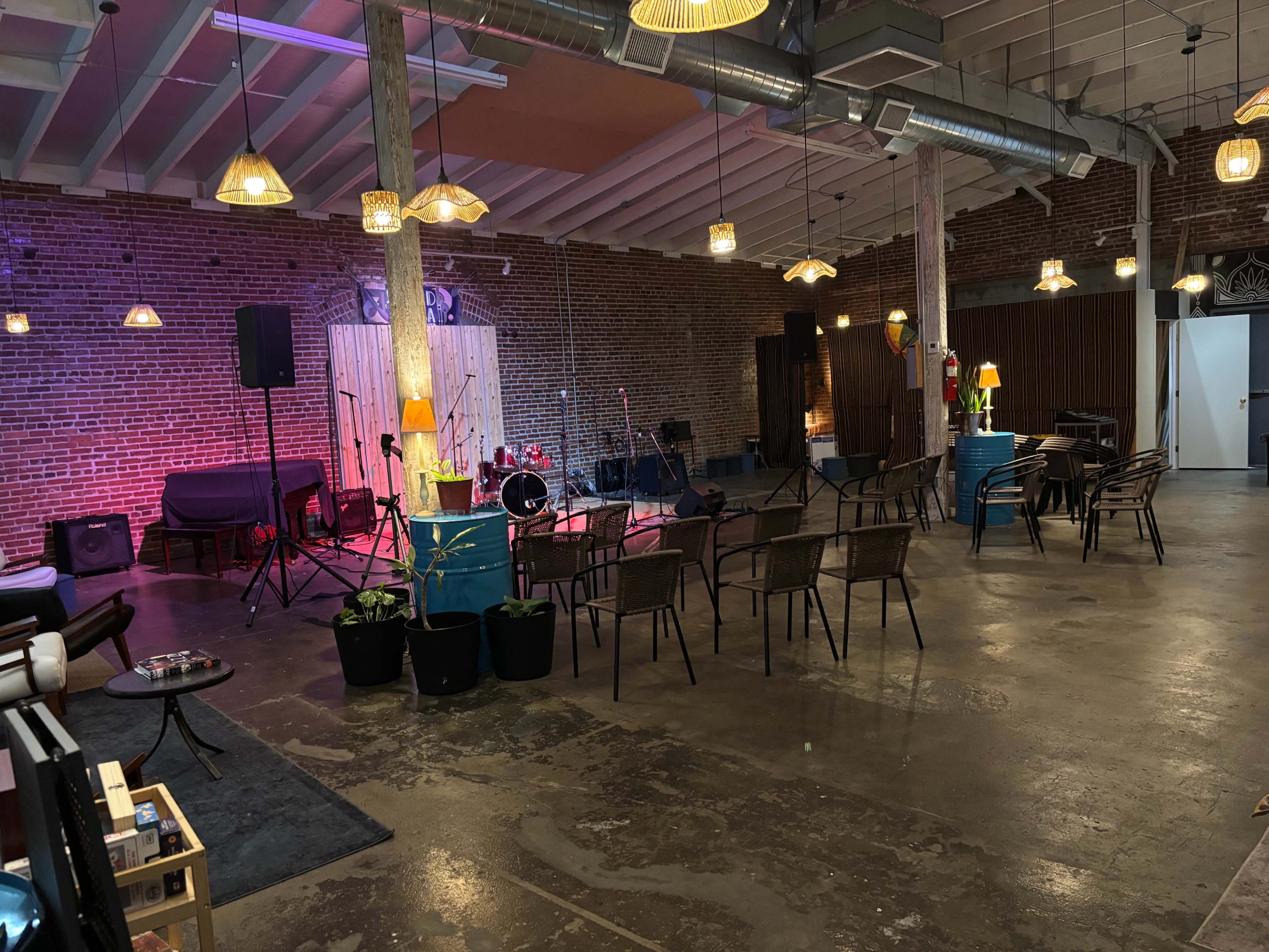 The image shows an indoor venue with a stage set for a performance, featuring seating arrangements and decorative lights.