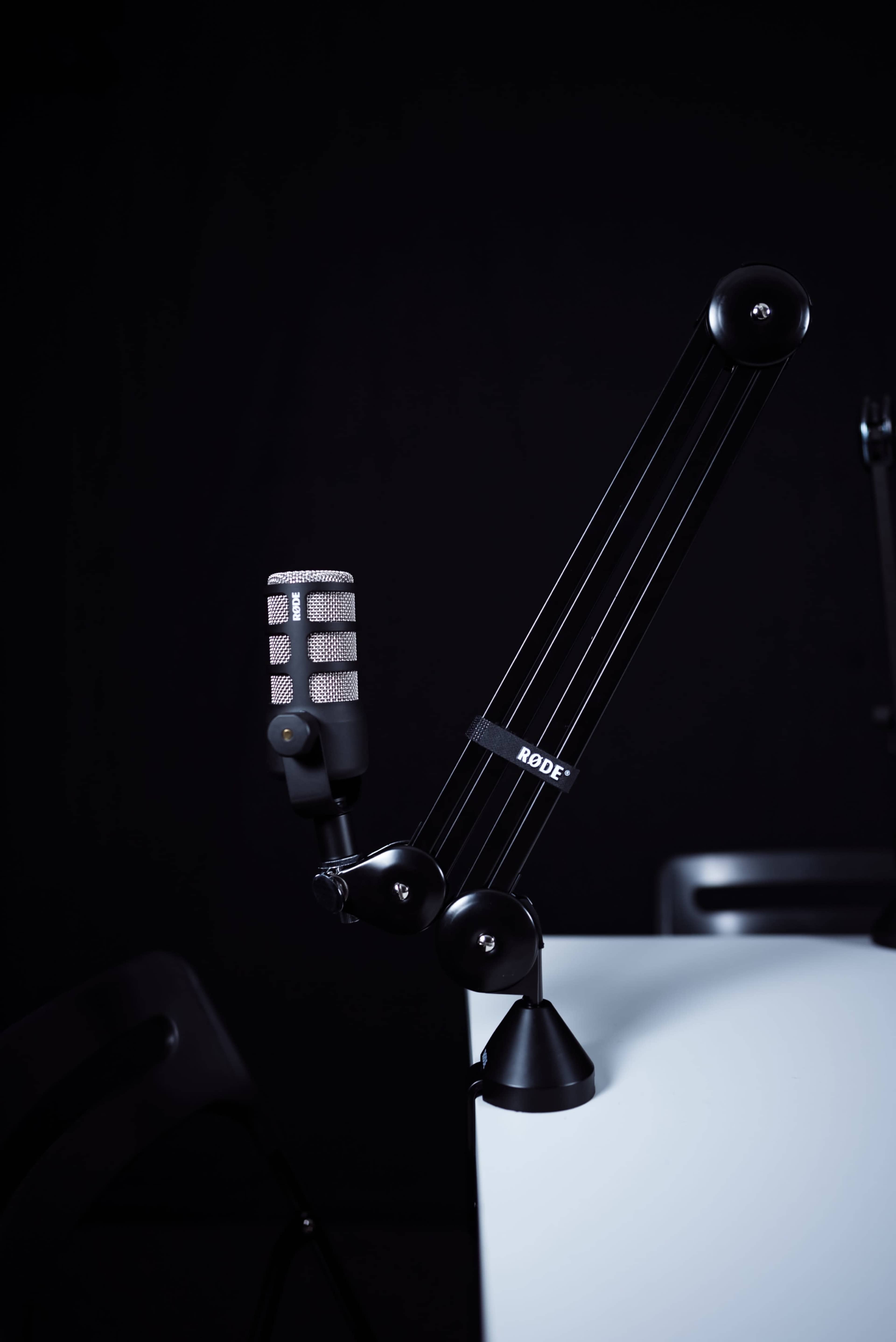 A microphone on an adjustable stand is positioned beside a white table against a black background.