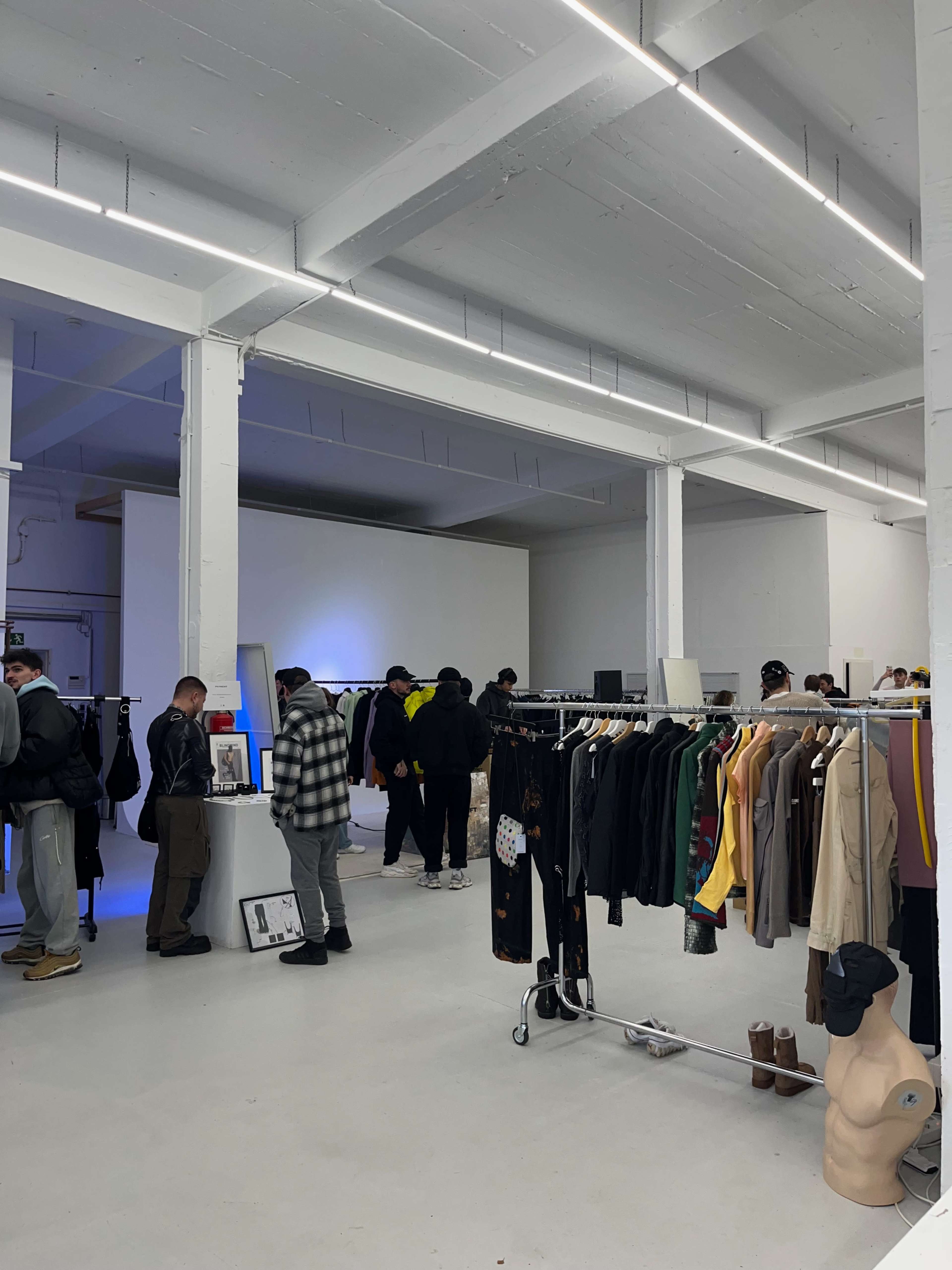 A spacious retail store features racks of clothing and several customers browsing the merchandise.