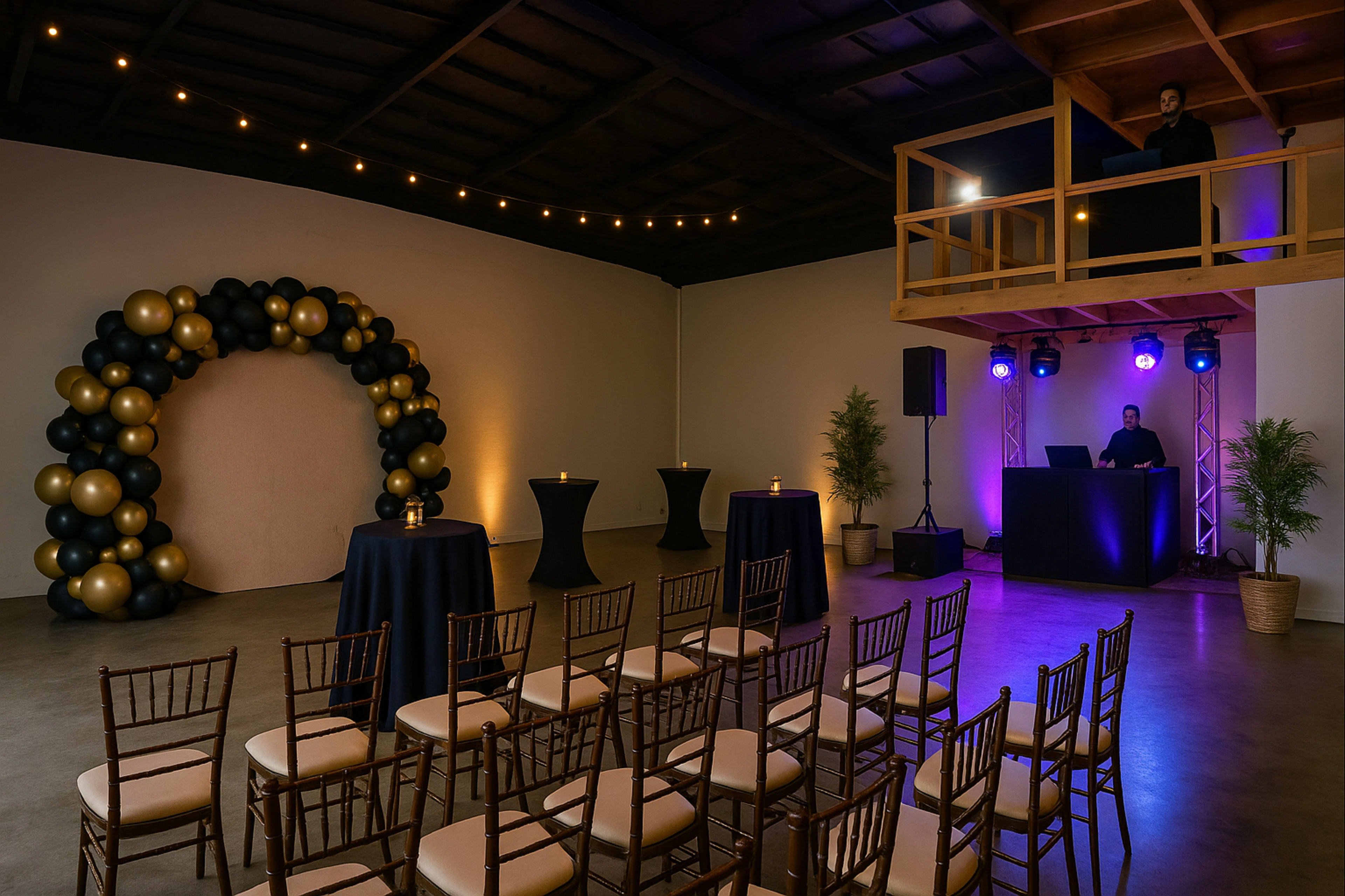 The image depicts a spacious event space with a decorative balloon arch, cocktail tables, rows of chairs, and a DJ setup under soft lighting.