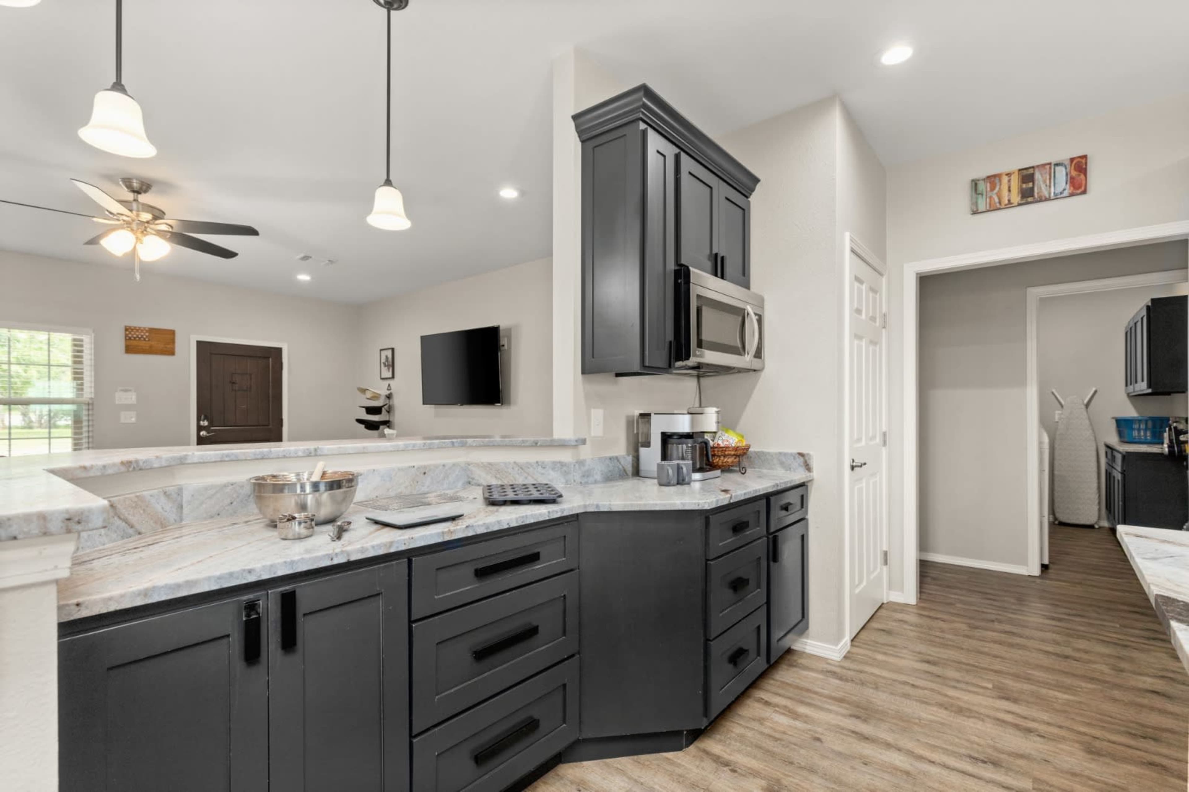 The kitchen features black cabinetry, a marble countertop, and modern appliances, with an open layout connecting to a living area.