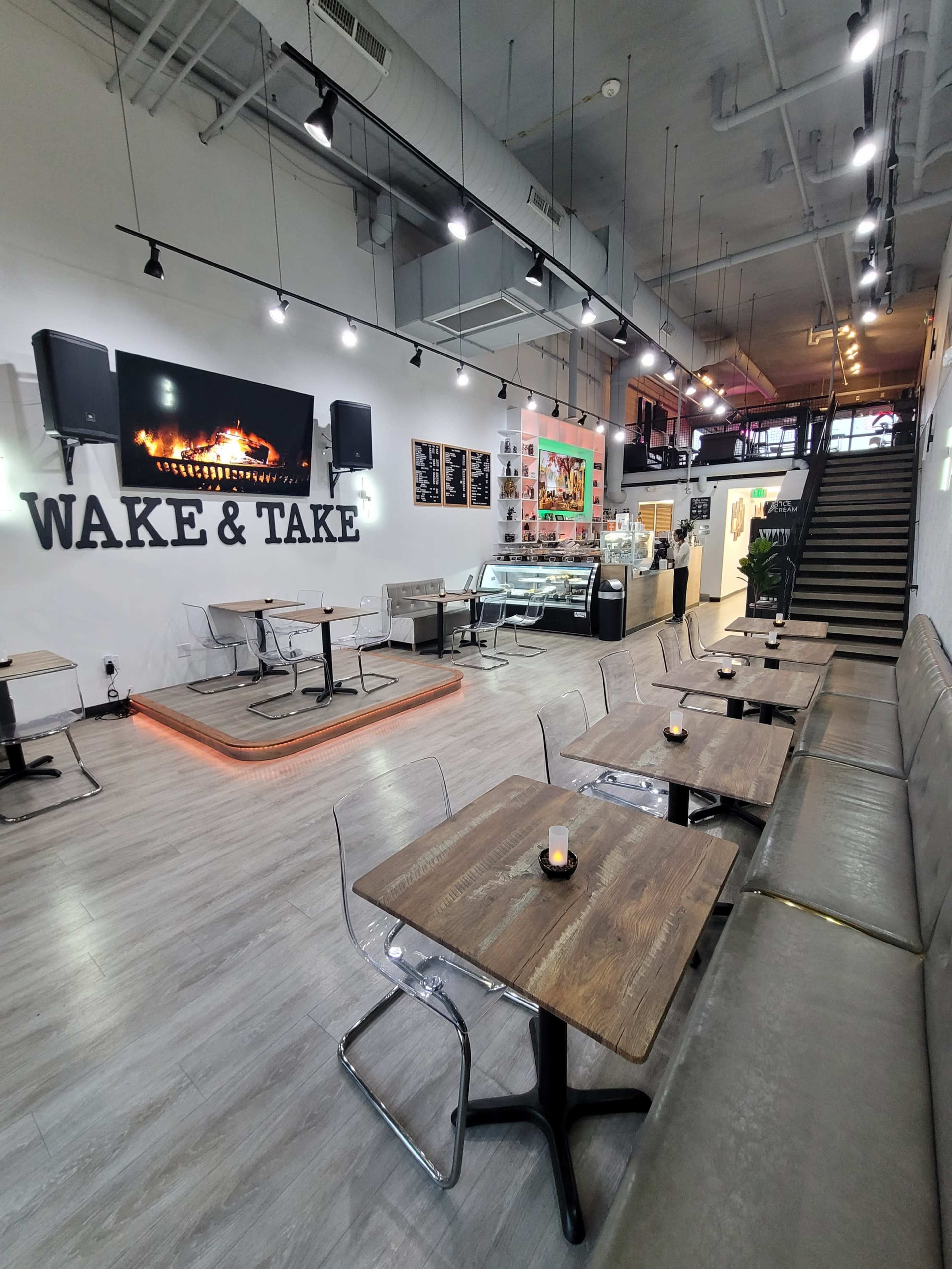 A modern café with wooden tables, clear chairs, and a counter displaying food and drinks, all set in a well-lit space.