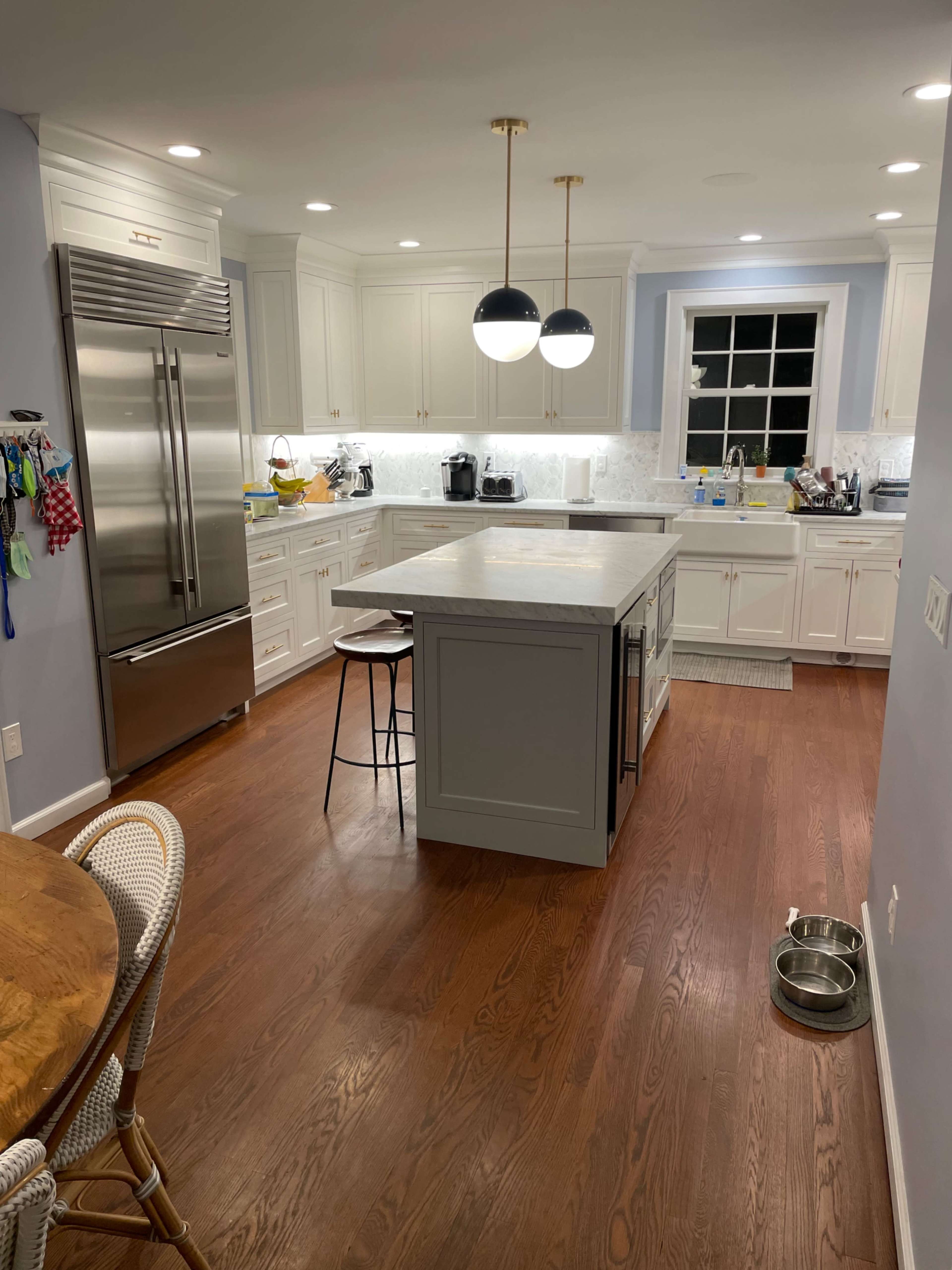 A modern kitchen features white cabinetry, stainless steel appliances, and a central island with a light gray countertop.