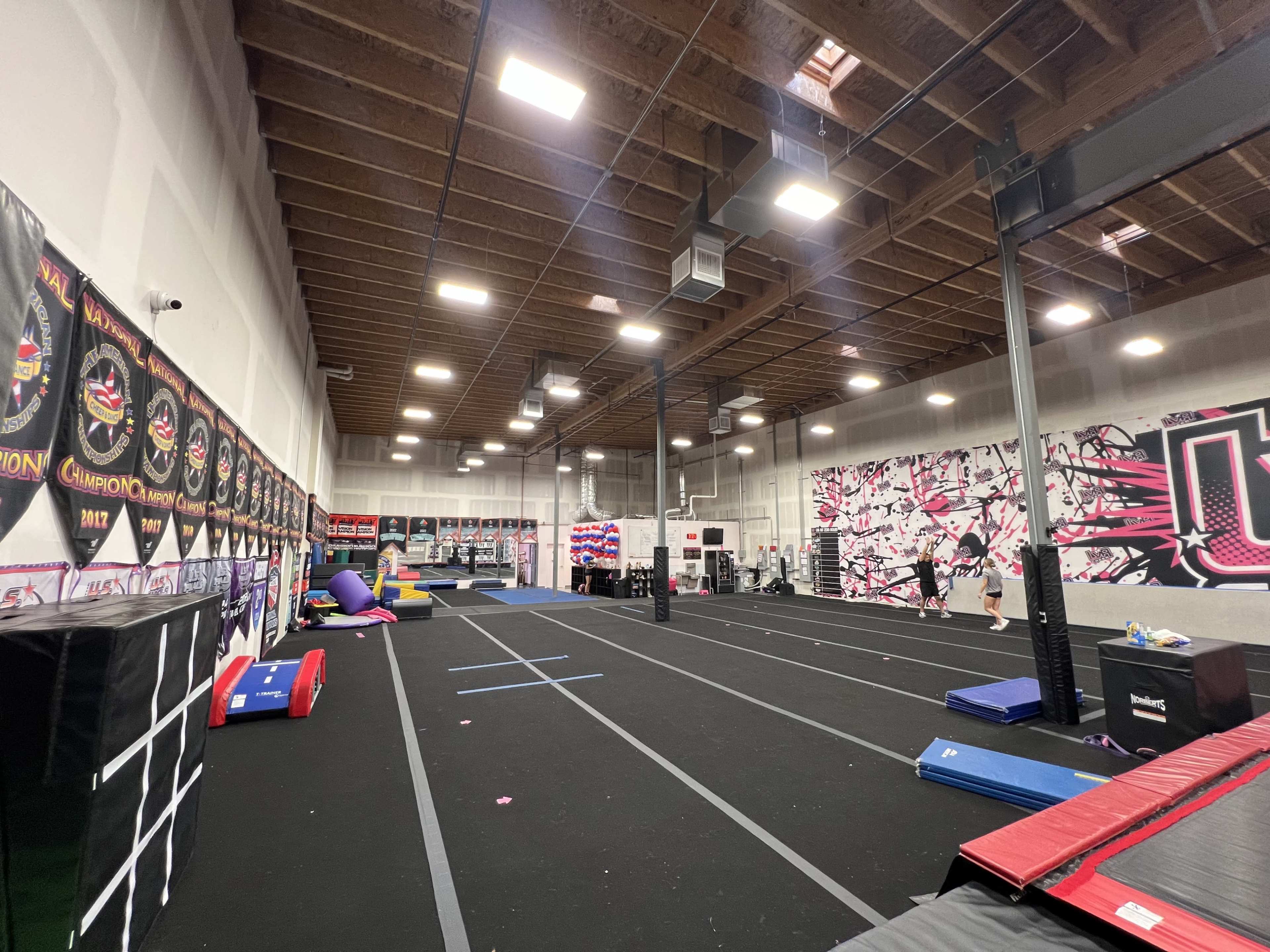 An indoor gym space with various exercise mats, equipment, and a wall decorated with colorful artwork.