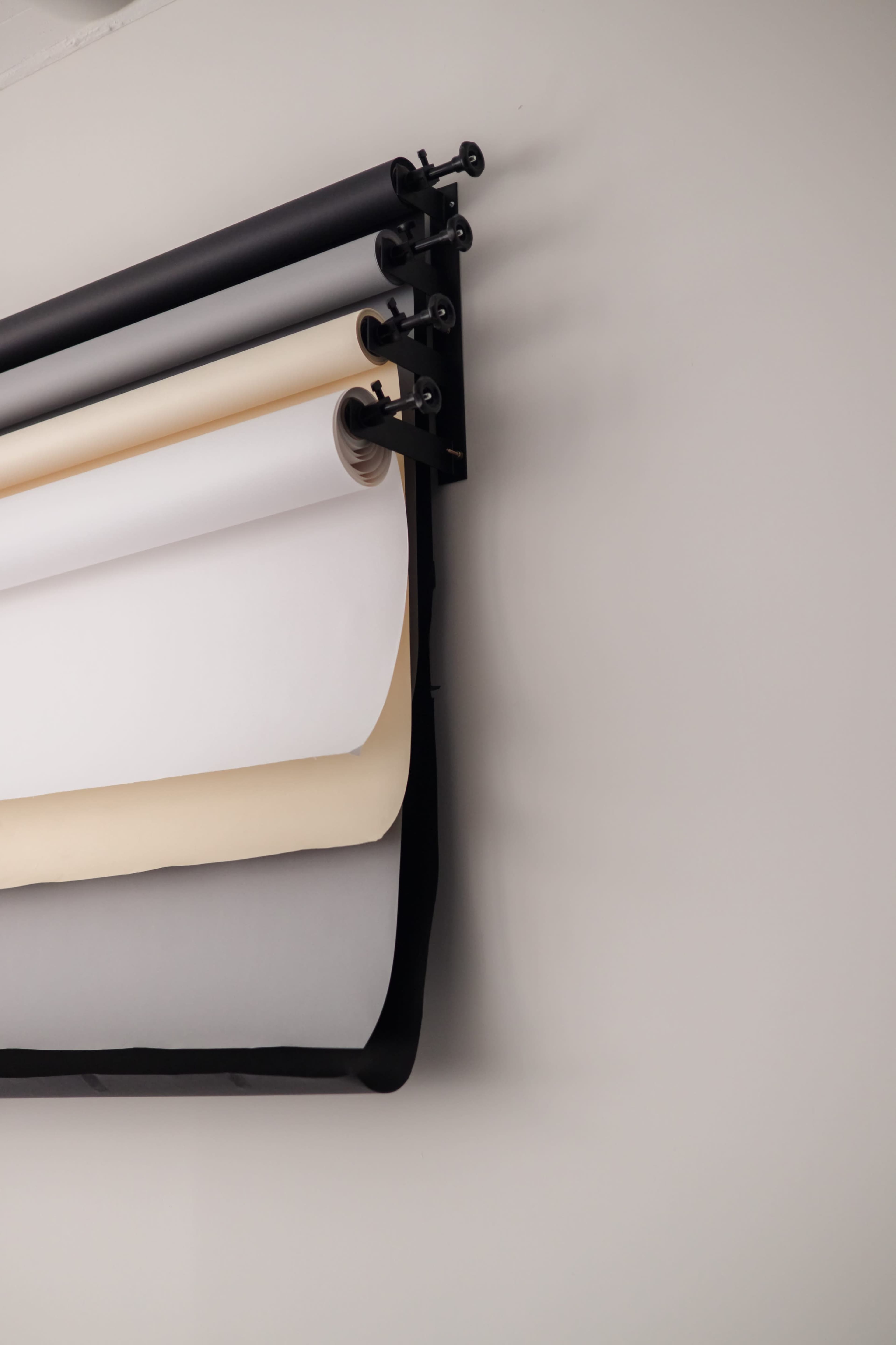 A wall-mounted roll of various colored paper is displayed on a black rack.