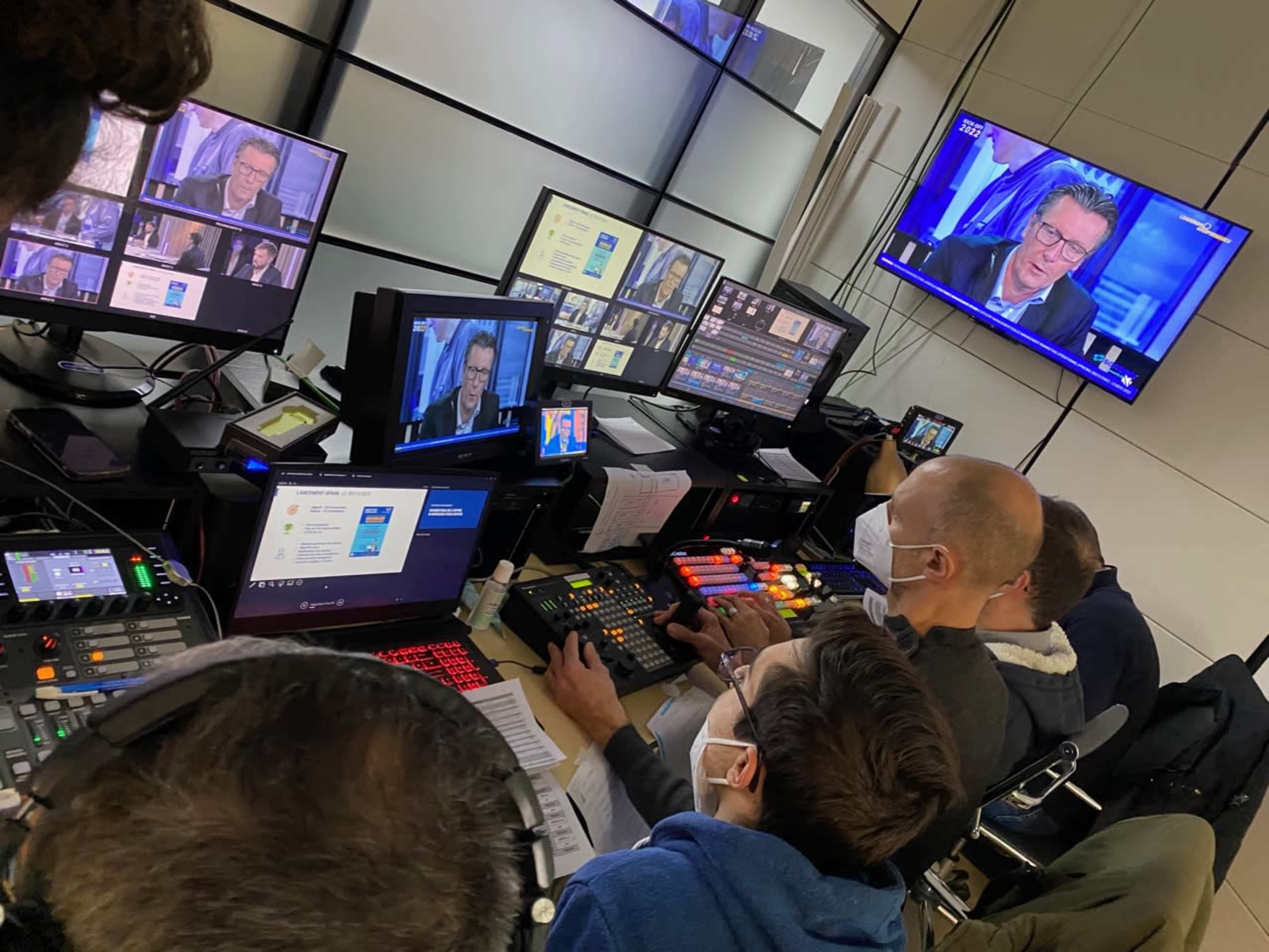 A group of technicians operates broadcasting equipment in a control room while monitoring multiple screens displaying a television program.