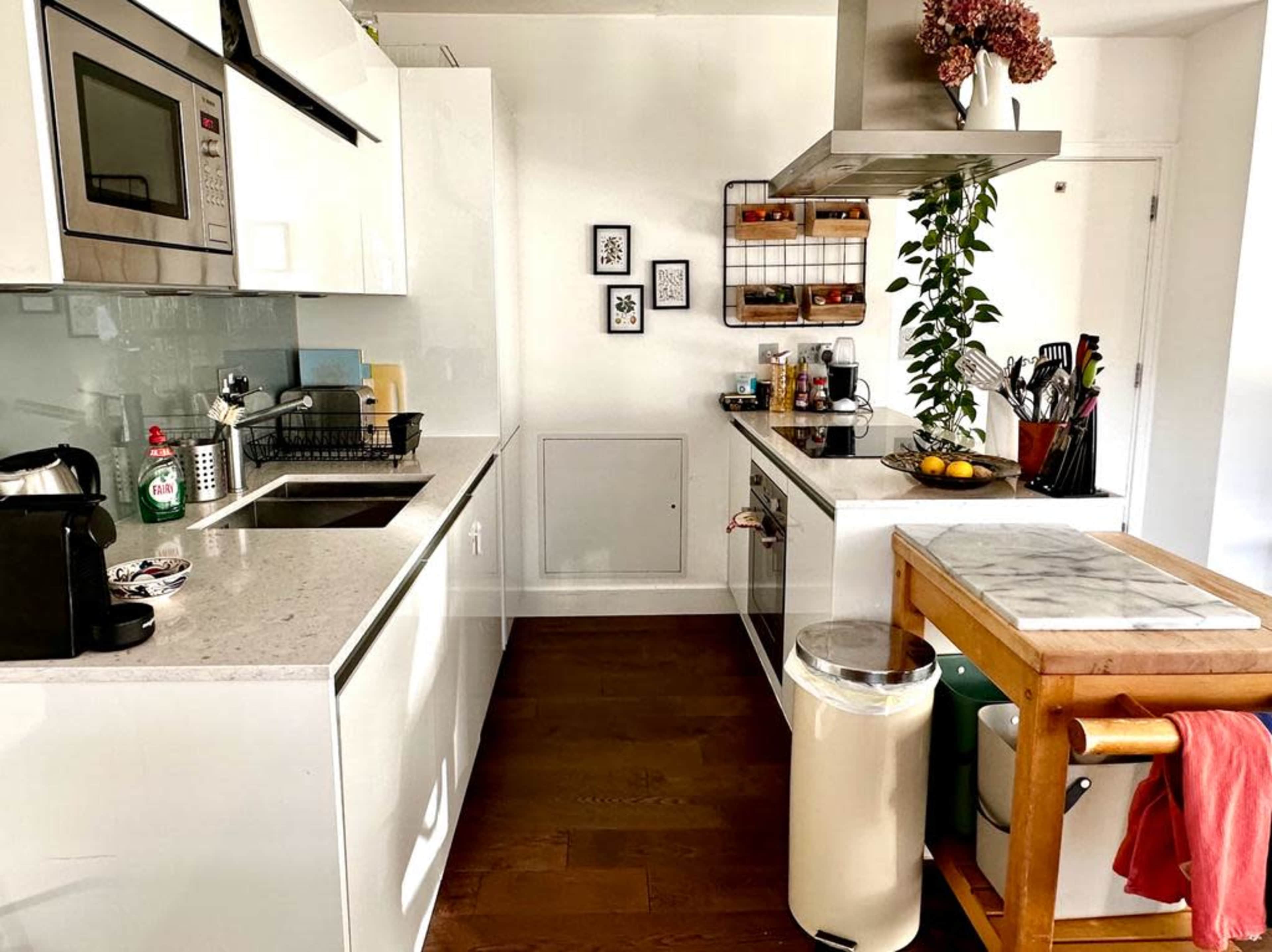 A modern kitchen with white cabinetry, a marble-topped island, and various kitchen items organized on the counter.