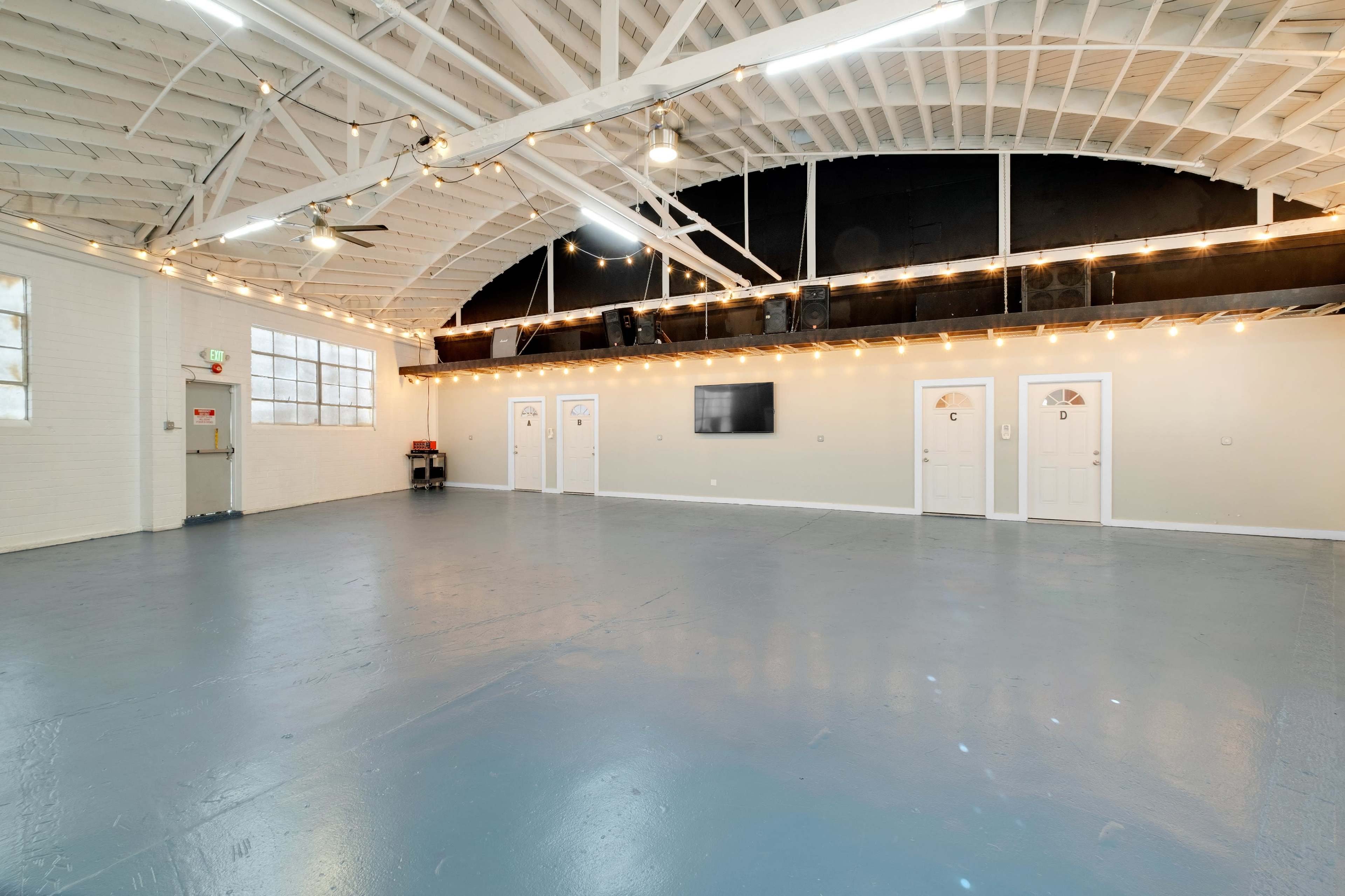 An empty, well-lit interior space with a polished floor, high ceiling, and several doors on one side.